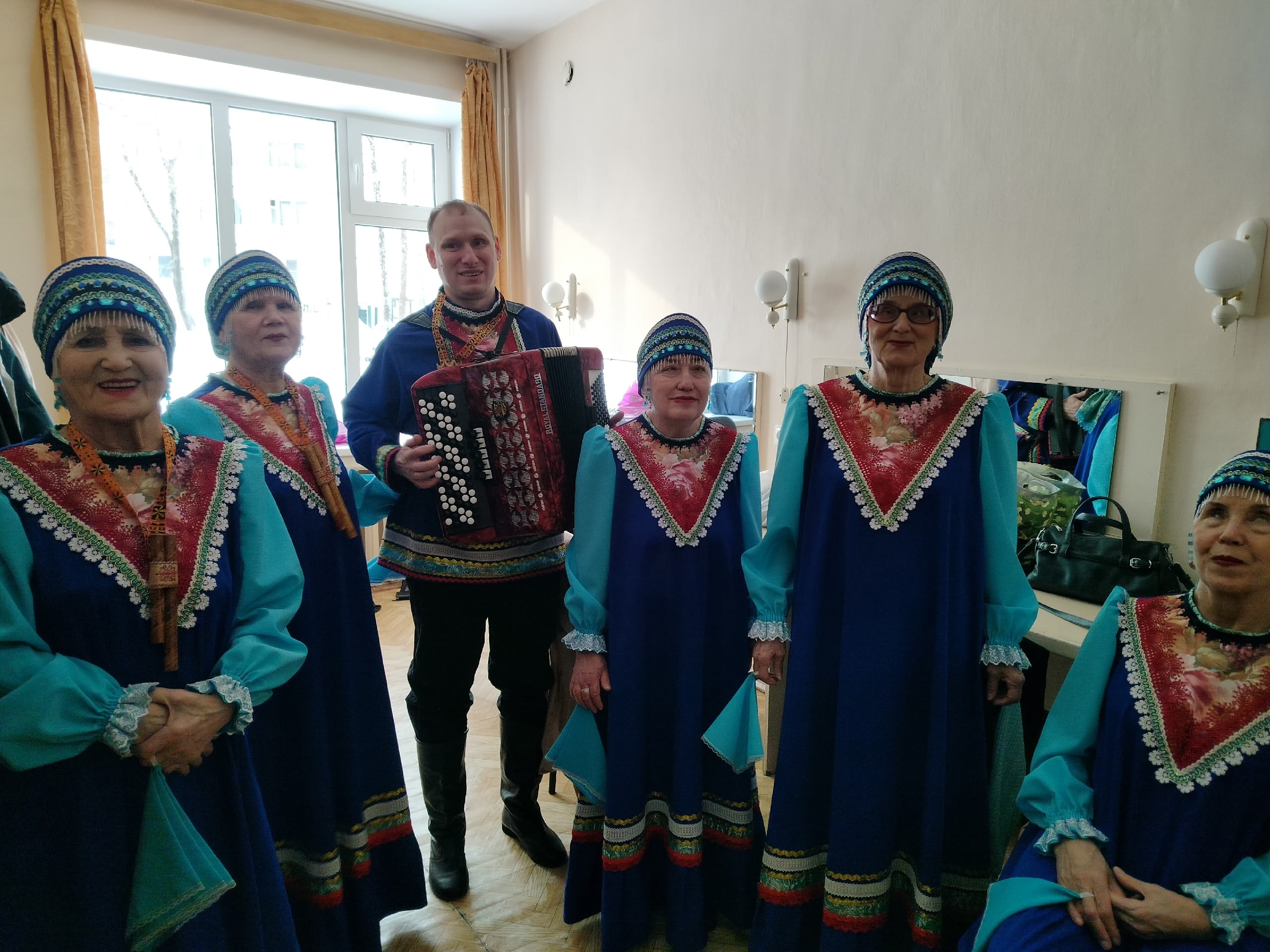 Ансамбль "Зорюшка" в народных костюмах и аккомпаниатор с гармонью перед выступлением.