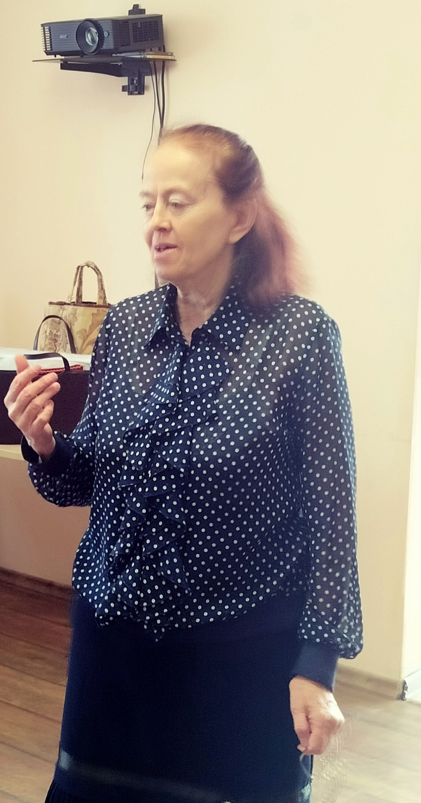 Елена Ароновна Толчинская в синей блузке в горошек жестикулирует, проводя мероприятие.