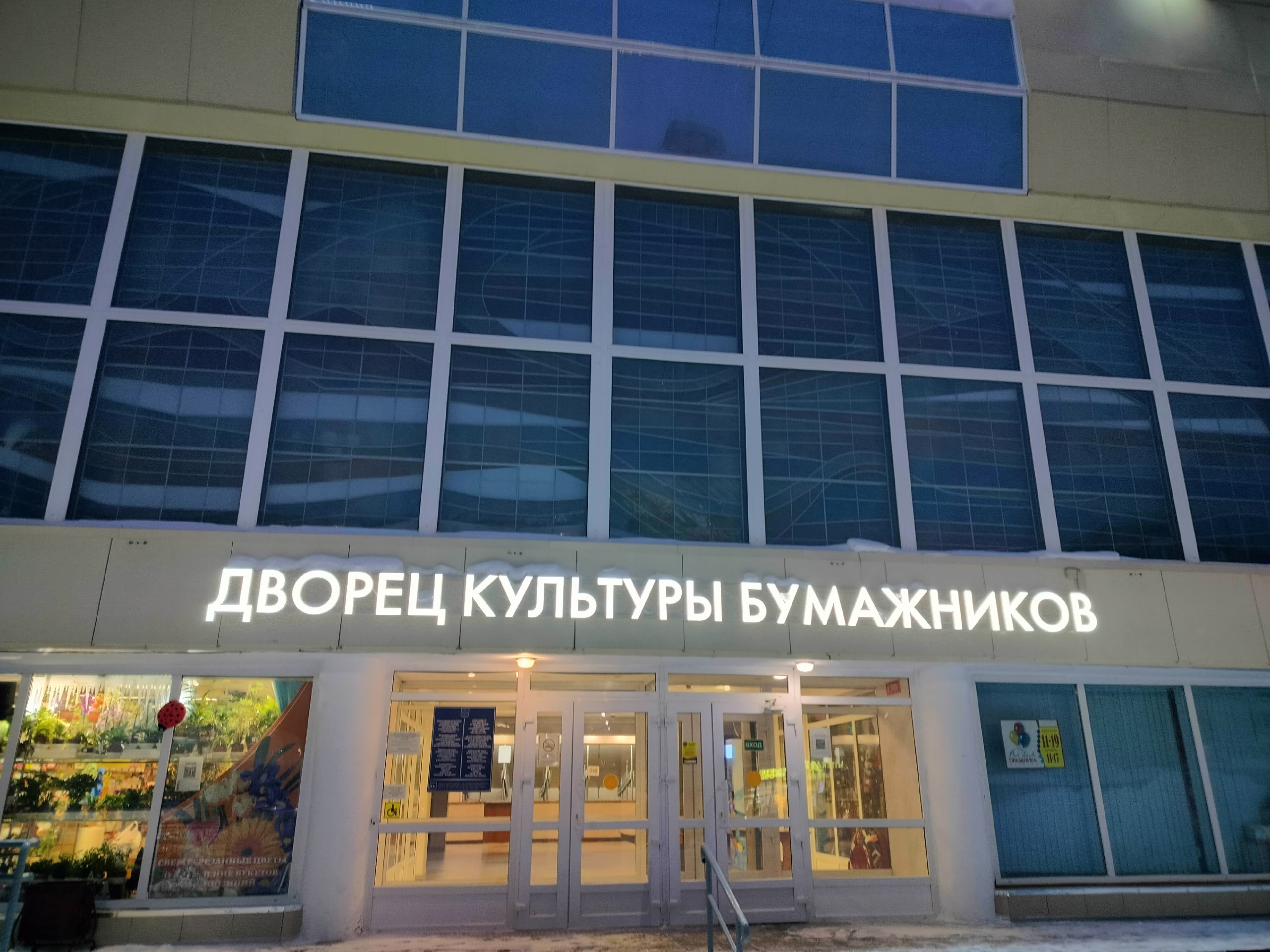 Фасад Дворца культуры Бумажников в Сыктывкаре с вывеской и освещенным входом.