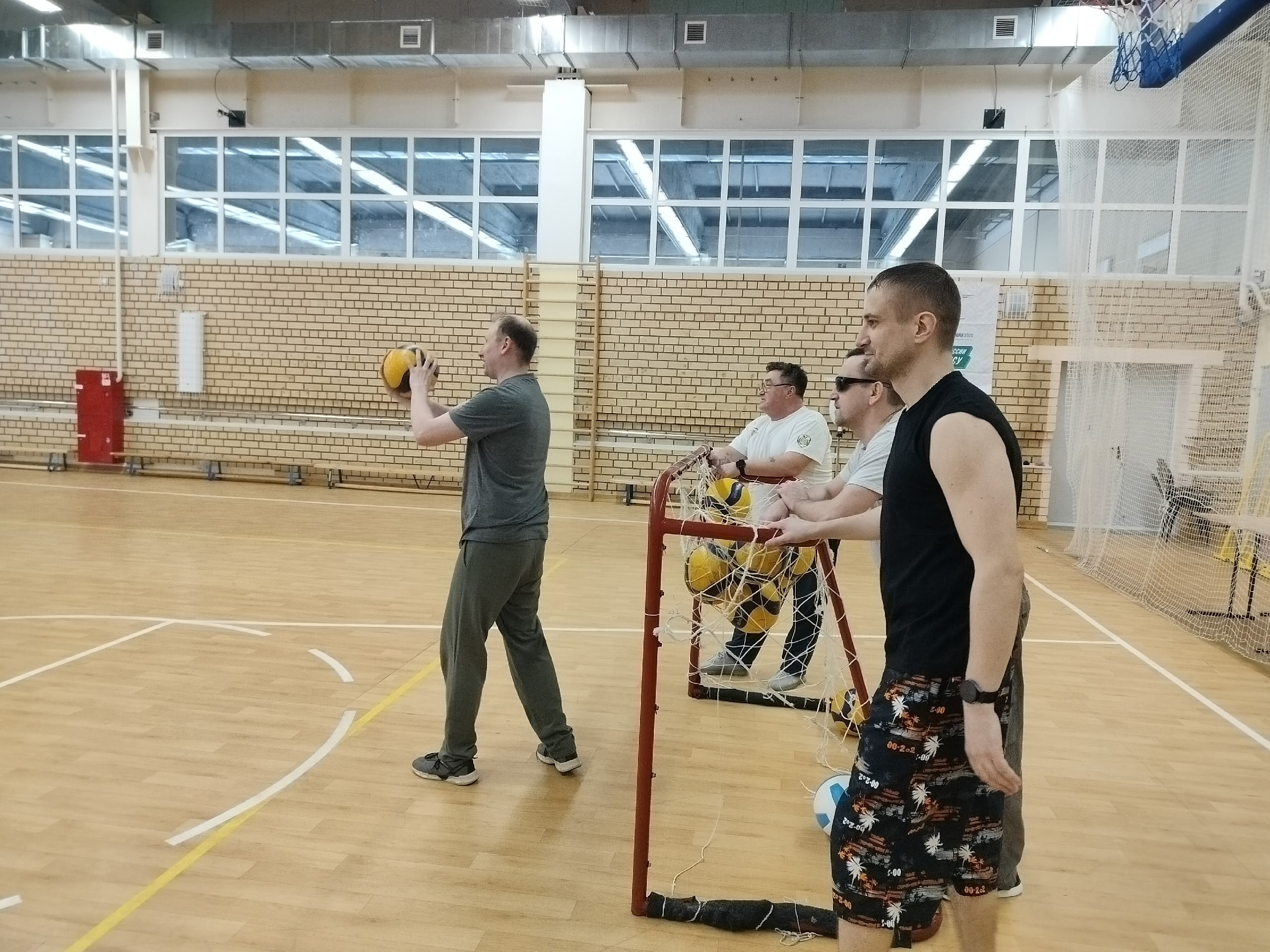 Мужчины тренируются с волейбольными мячами.