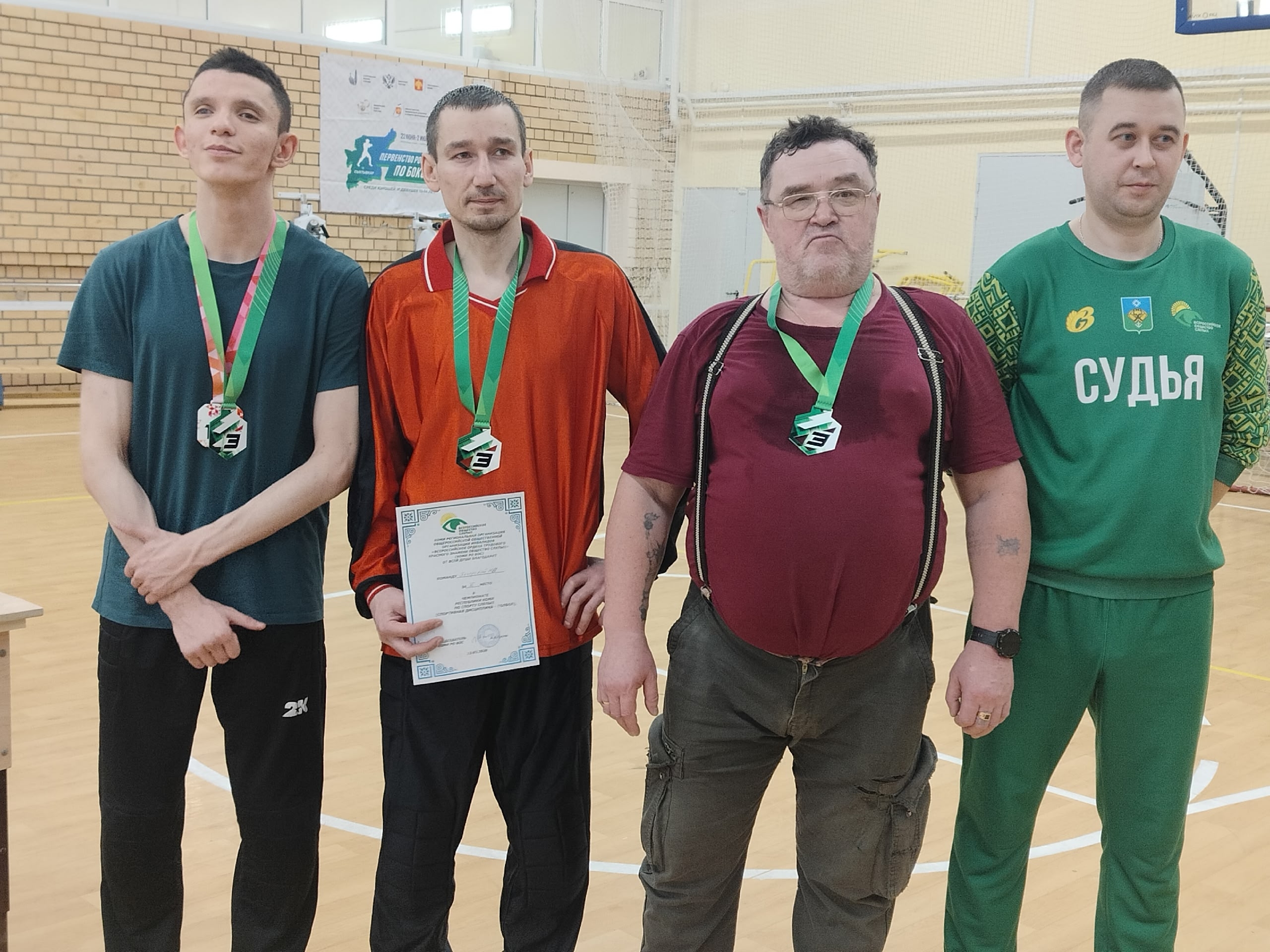 Четверо мужчин с медалями и сертификатом, один судья