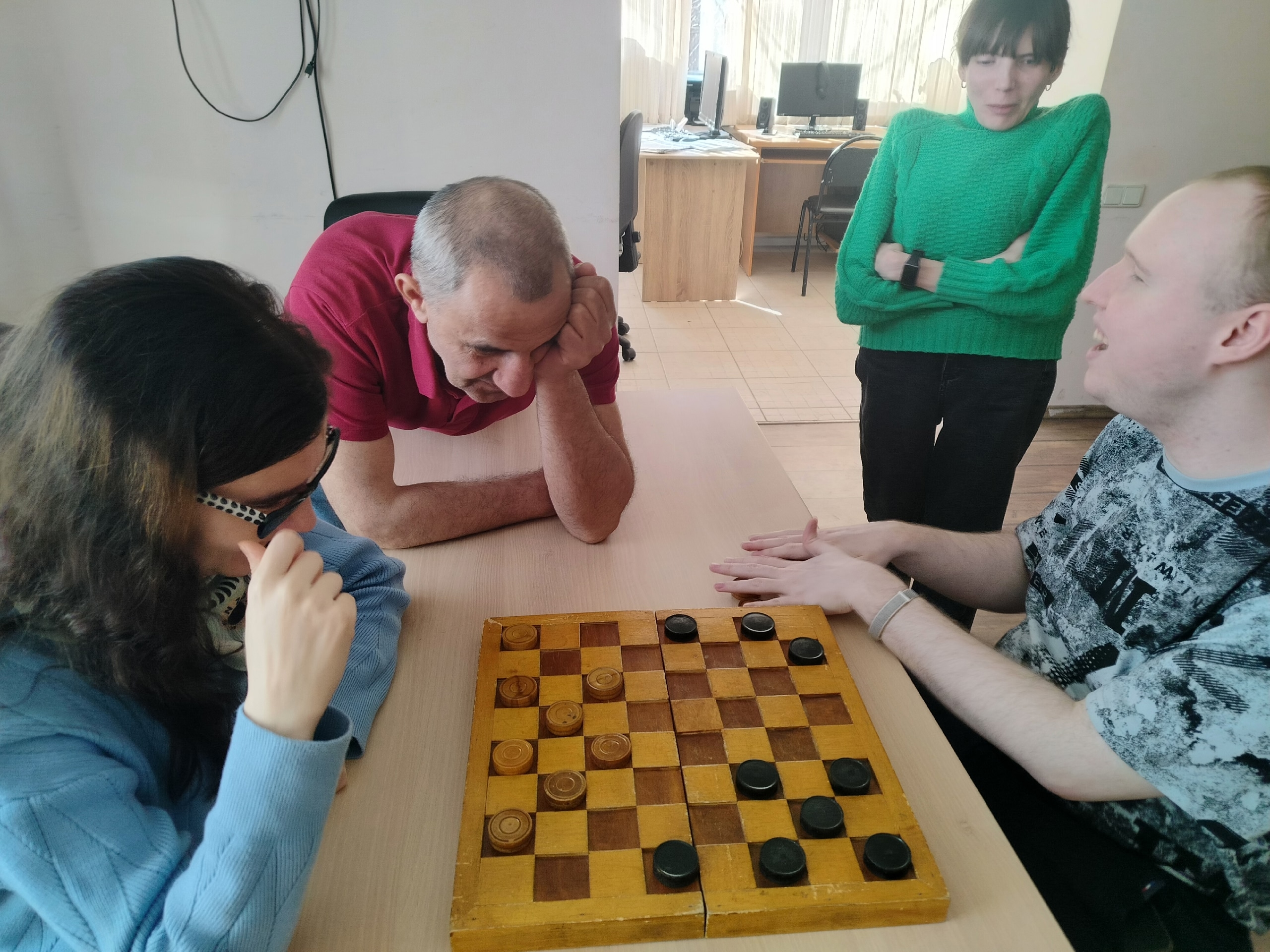 Люди играют в шашки за столом