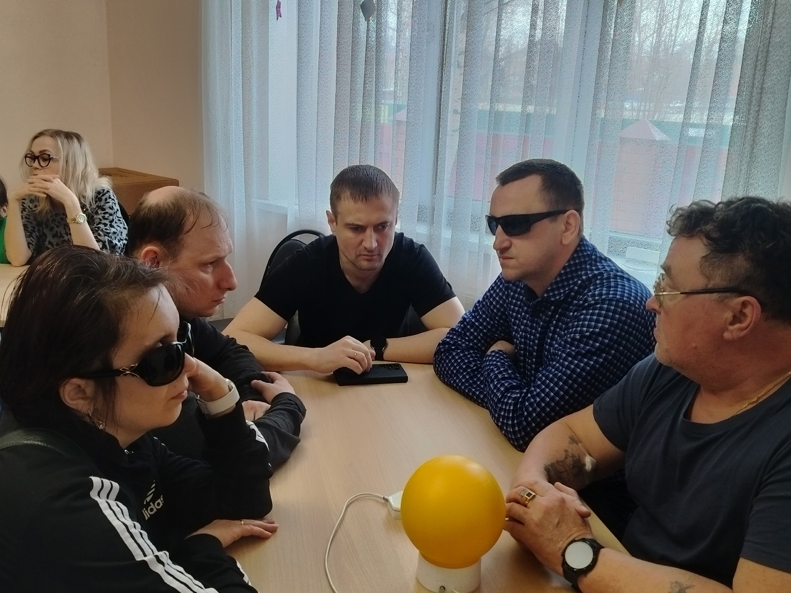 Люди за столом с желтым светящимся шаром