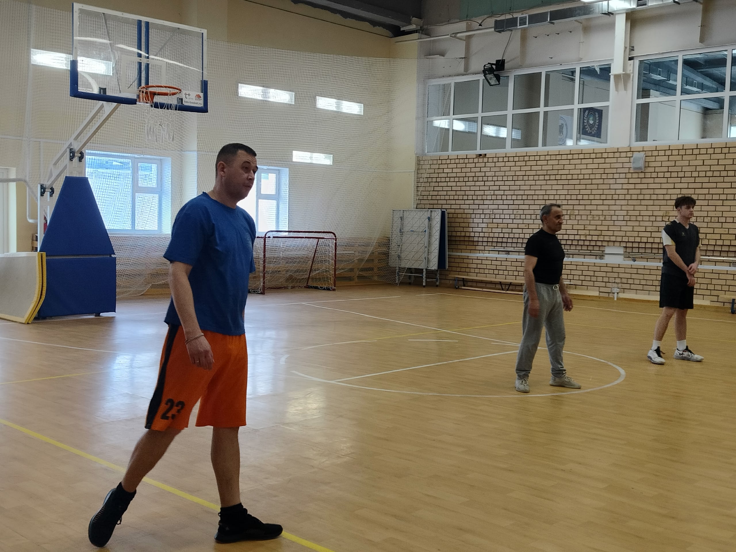 Три мужчины стоят на волейбольной площадке.