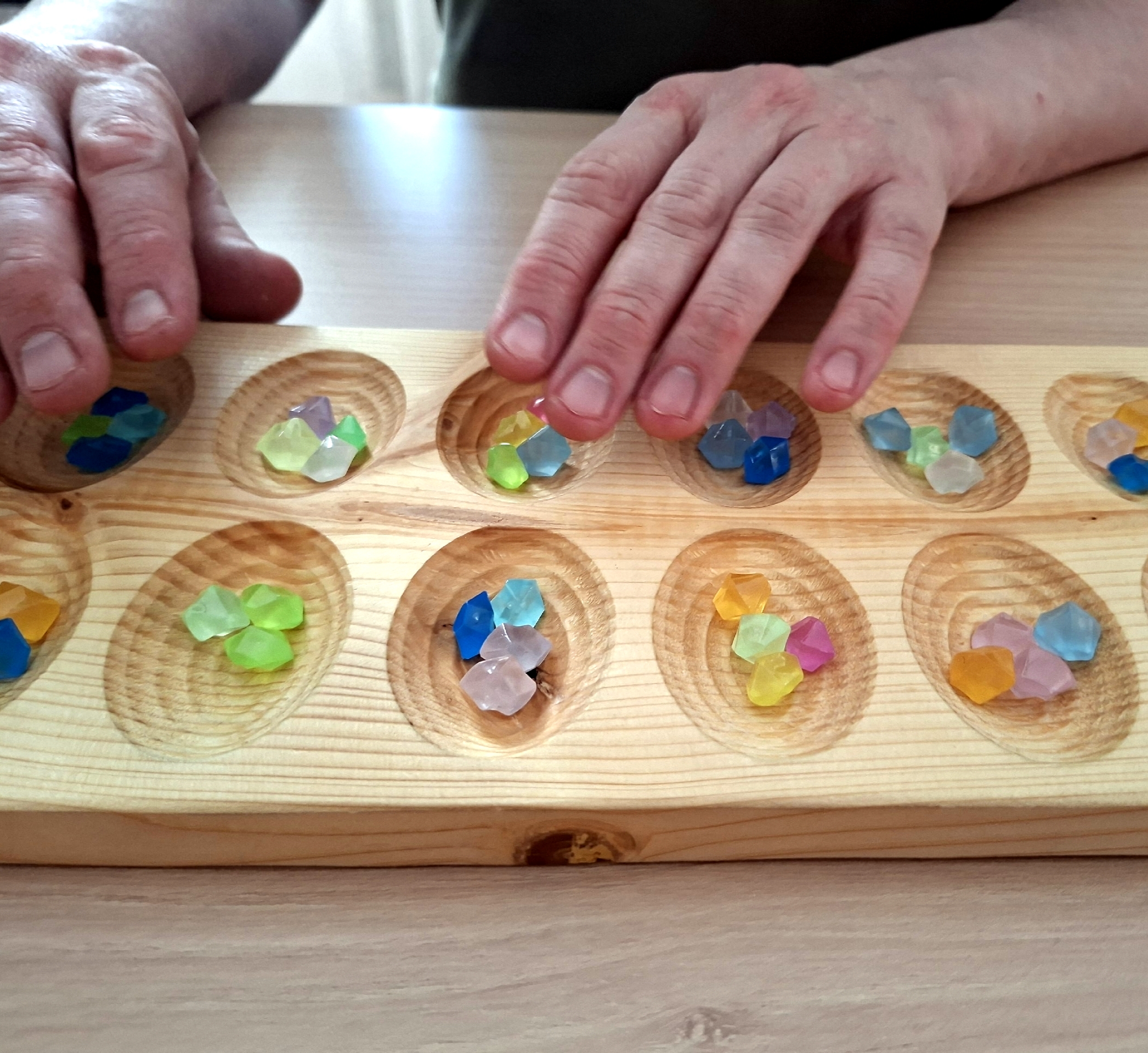 Руки играют в Калах с цветными фишками