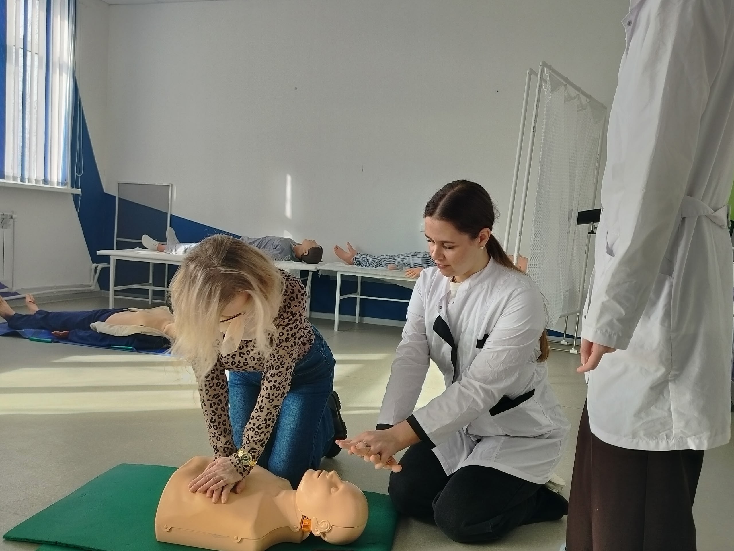 Женщина выполняет компрессии грудной клетки на учебном манекене.