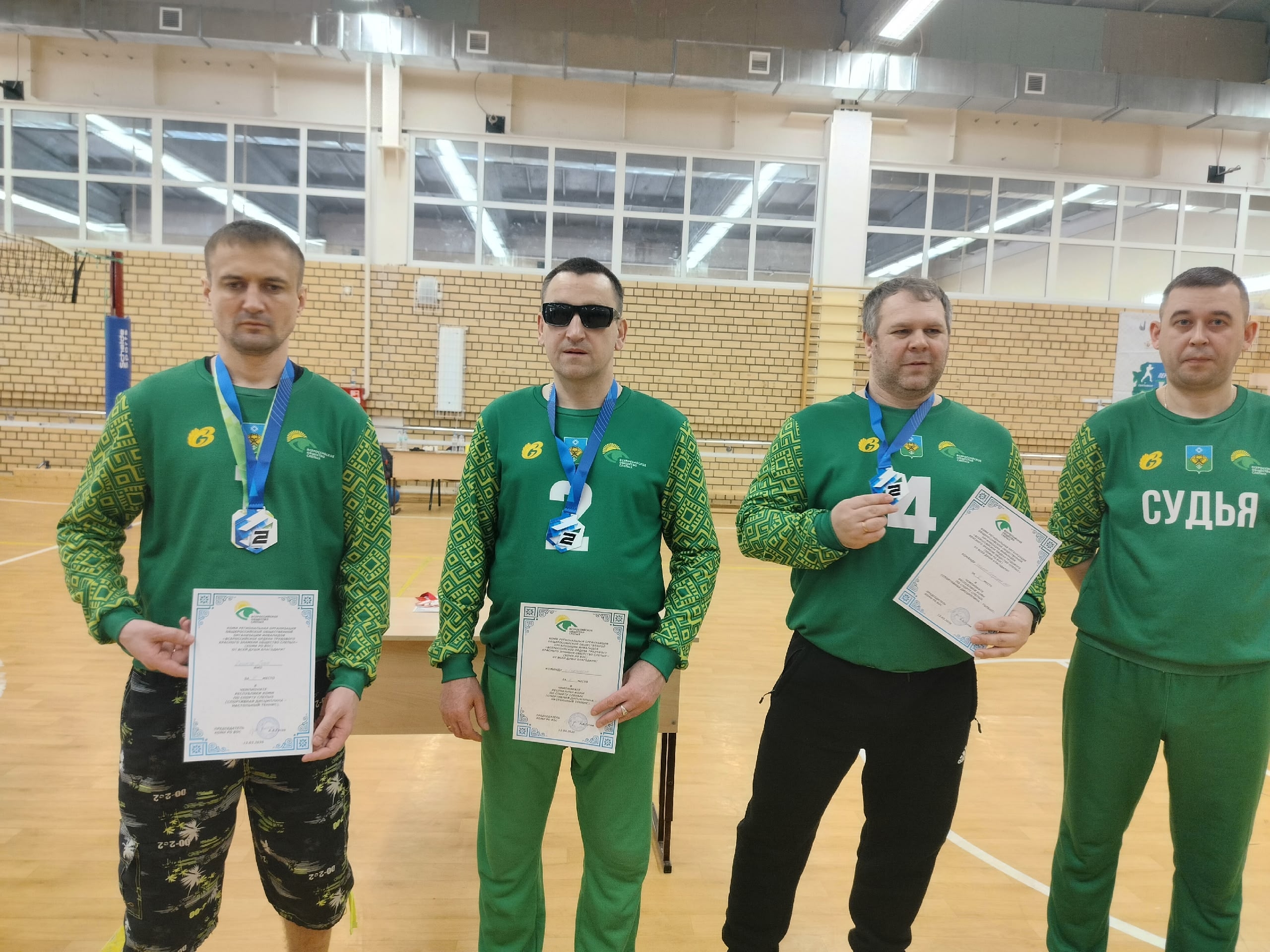 Четверо мужчин с медалями и сертификатами, один судья