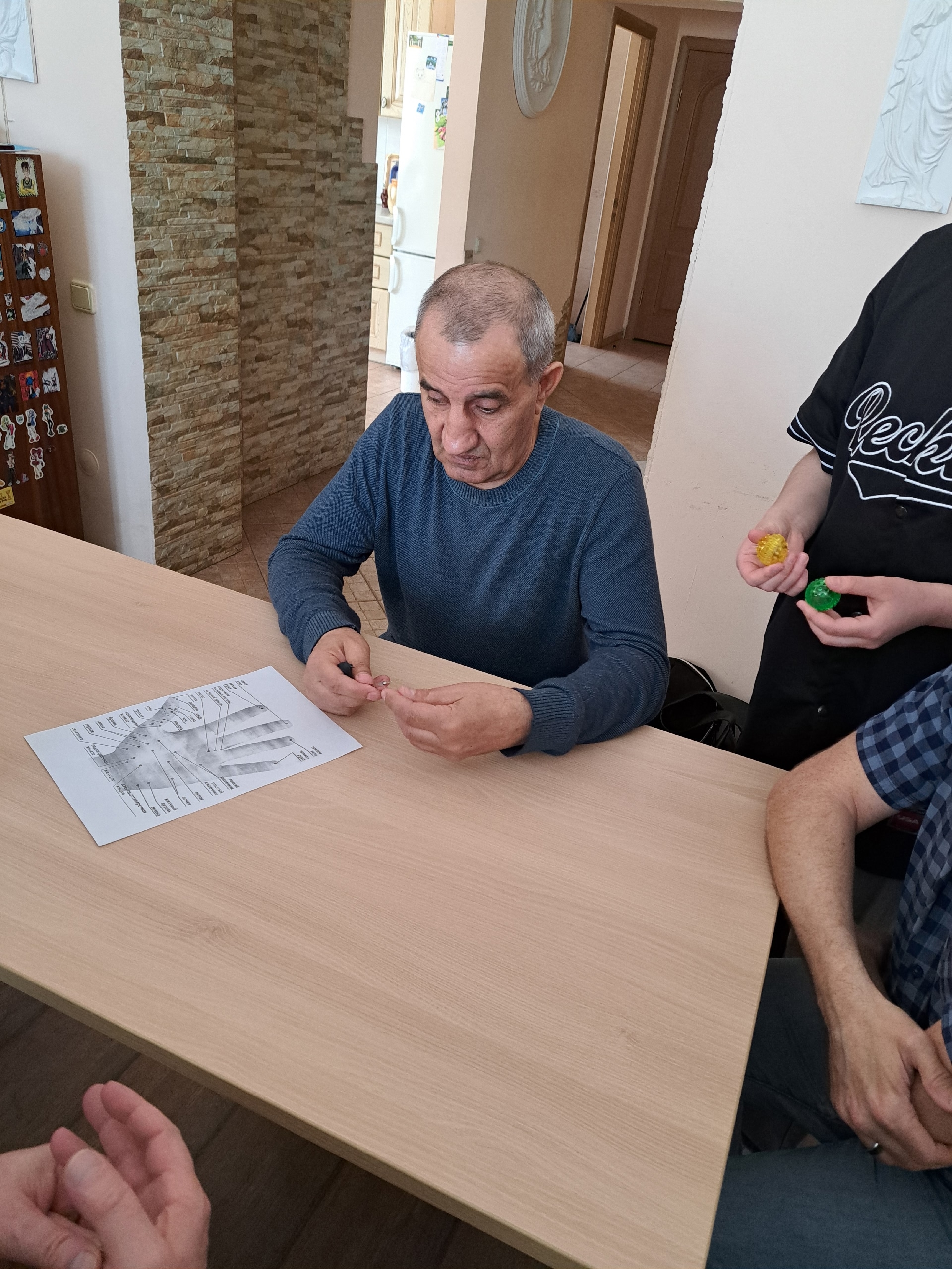 Мужчина изучает су-джок шарик и схему