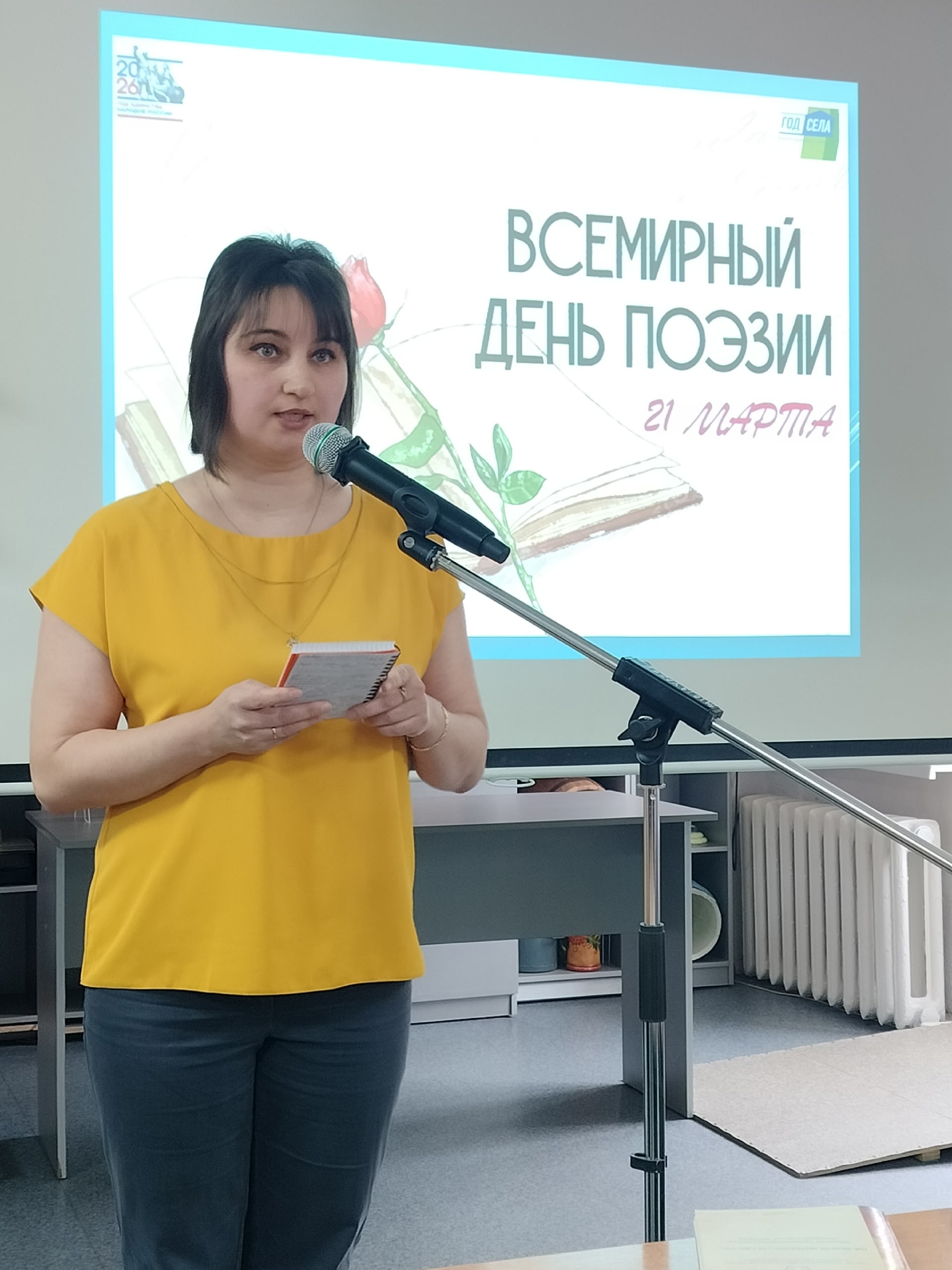 Женщина в желтой футболке выступает с микрофоном.