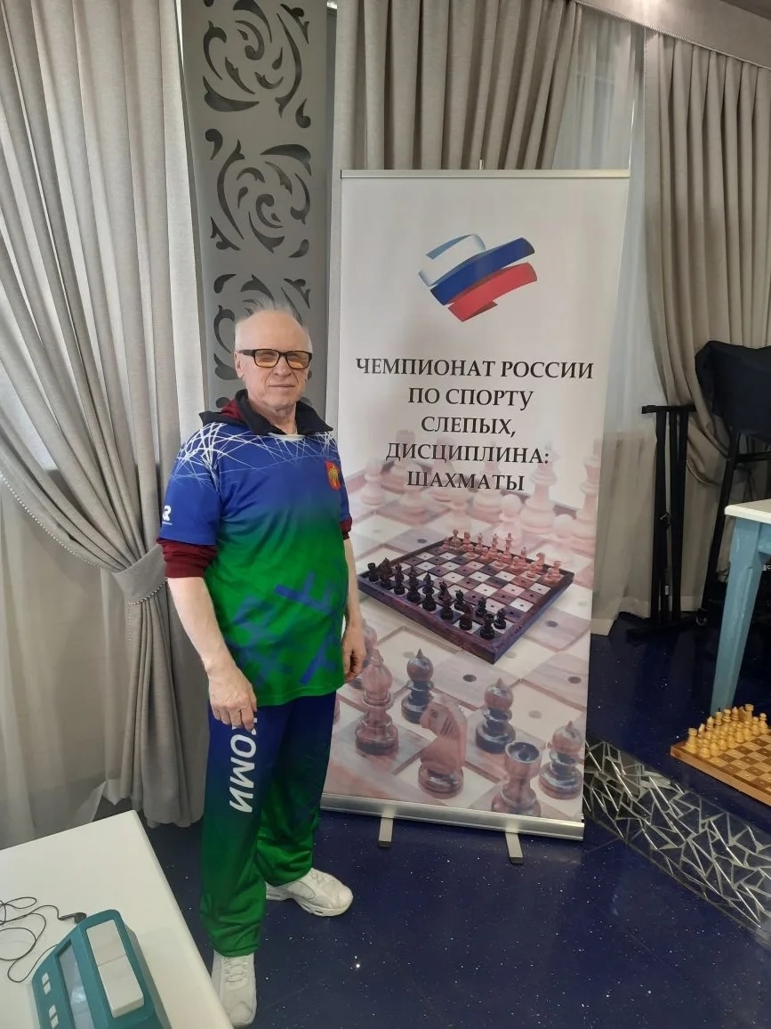 Александр Мартынов стоит у баннера чемпионата России по шахматам