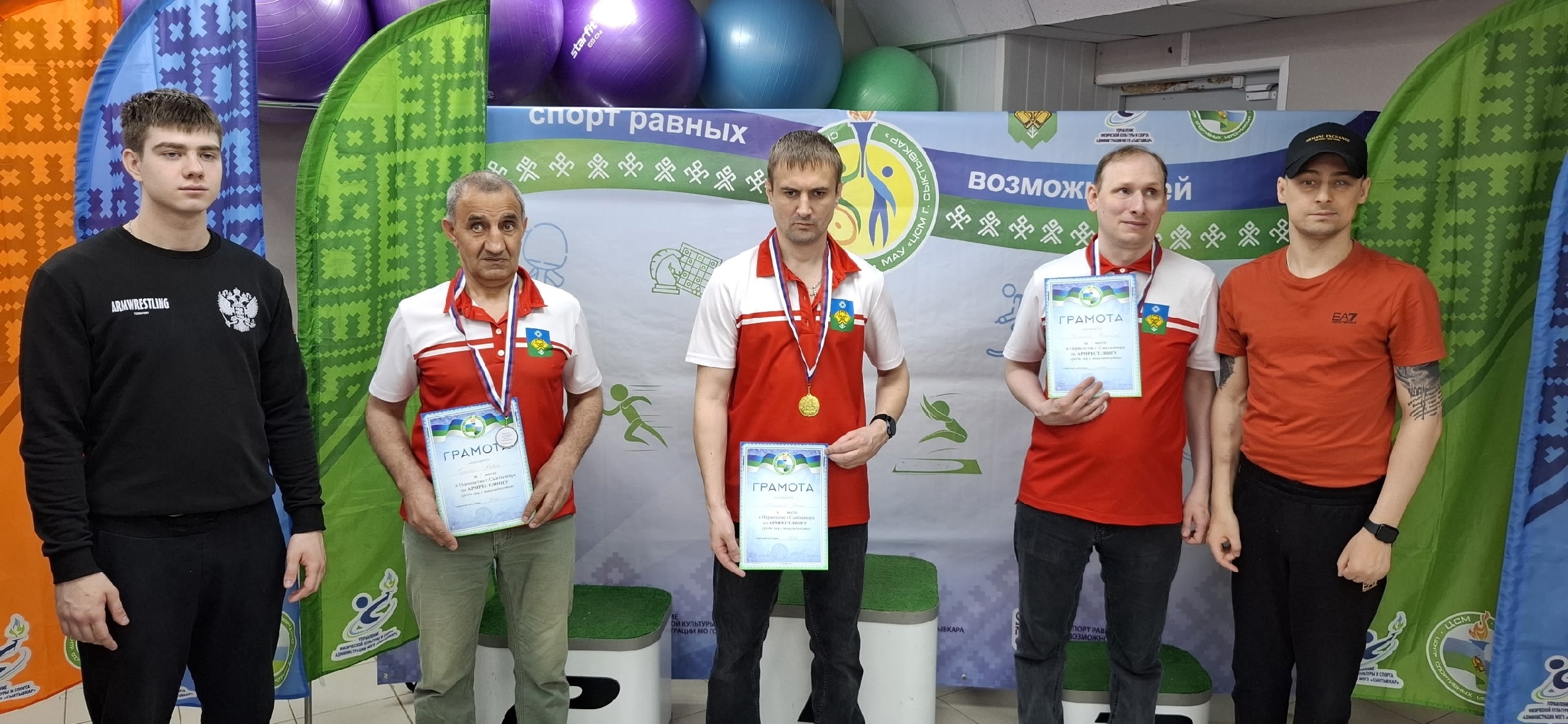 Пять мужчин с дипломами и медалями на фоне баннера