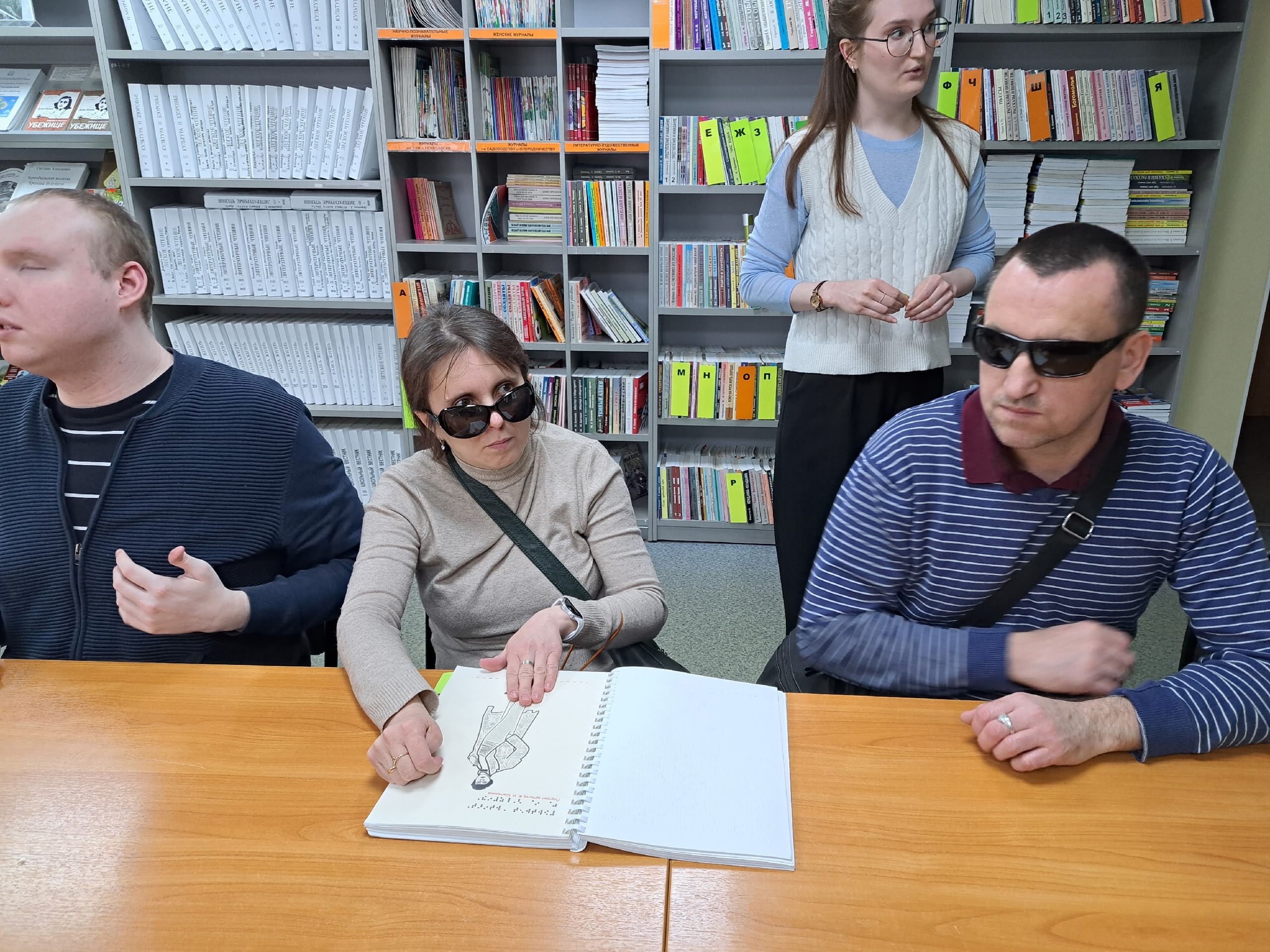 Люди с нарушениями зрения изучают тактильную книгу.
