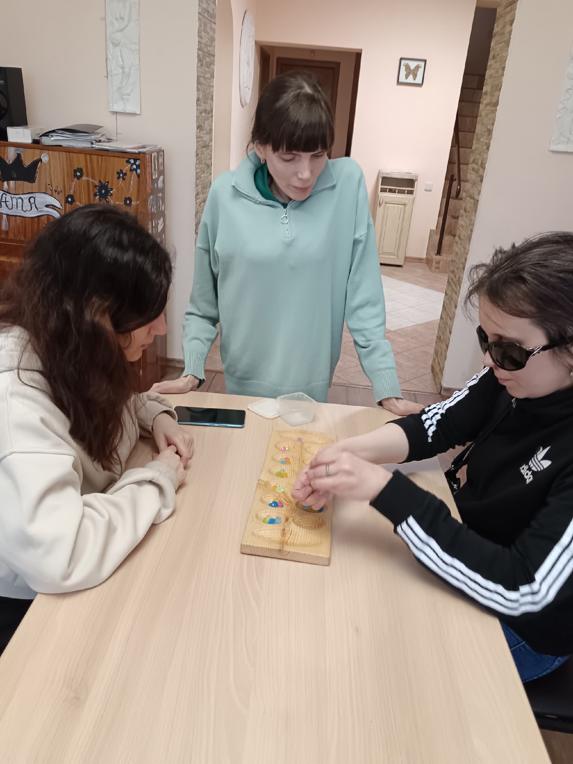 Женщины играют в настольные игры, одна наблюдает