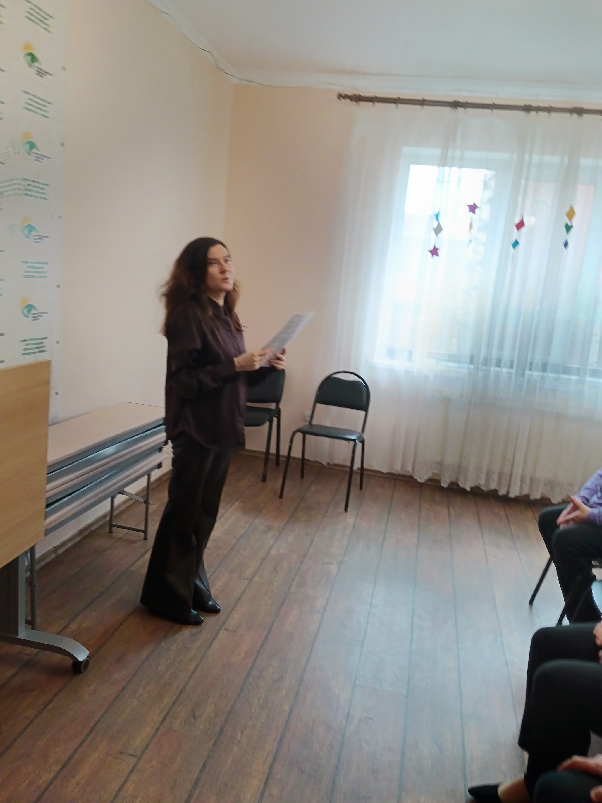 Женщина стоит в комнате и держит бумаги