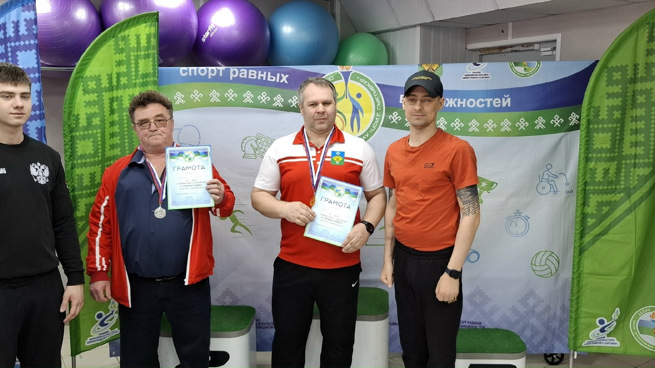 Пять мужчин с дипломами и медалями на фоне баннера