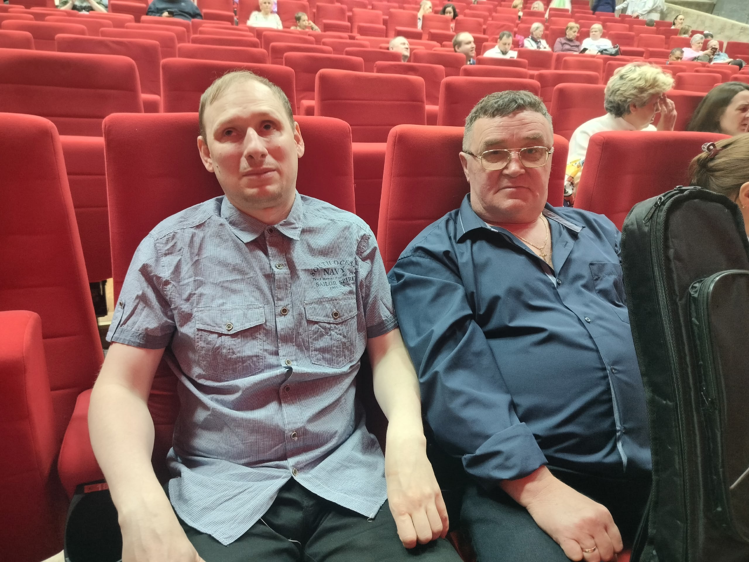 Два мужчины сидят в зрительном зале