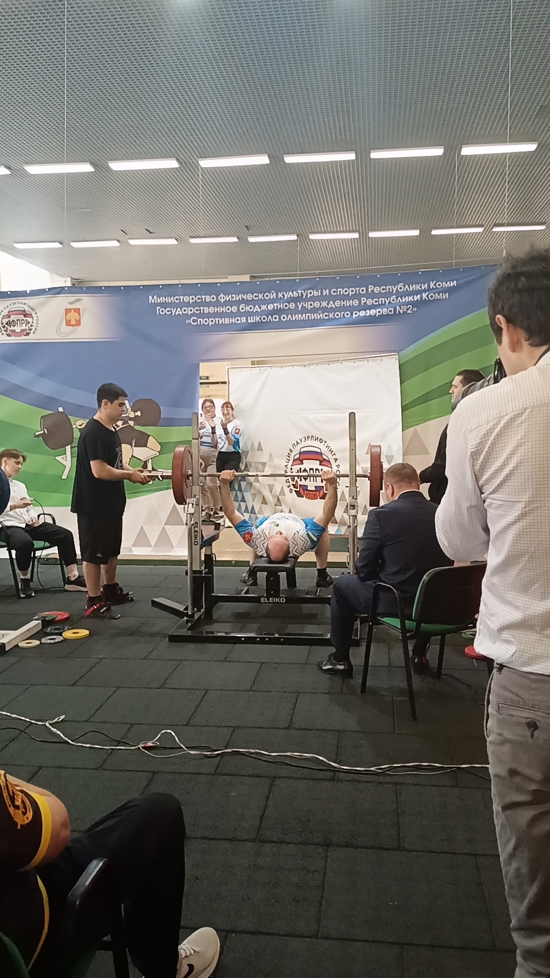Спортсмен в спортивной форме выжимает штангу лежа