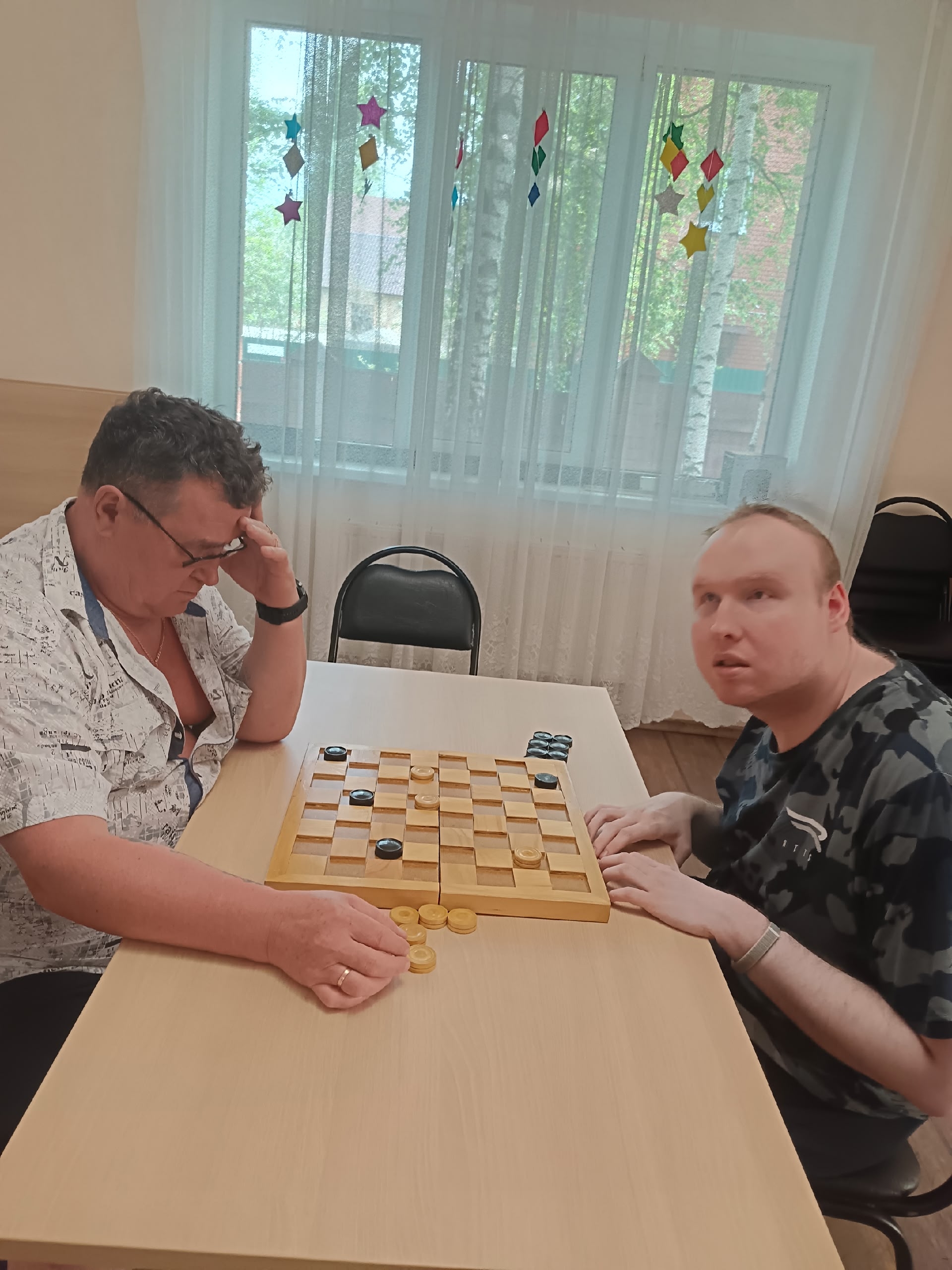 Двое мужчин играют в шашки за столом