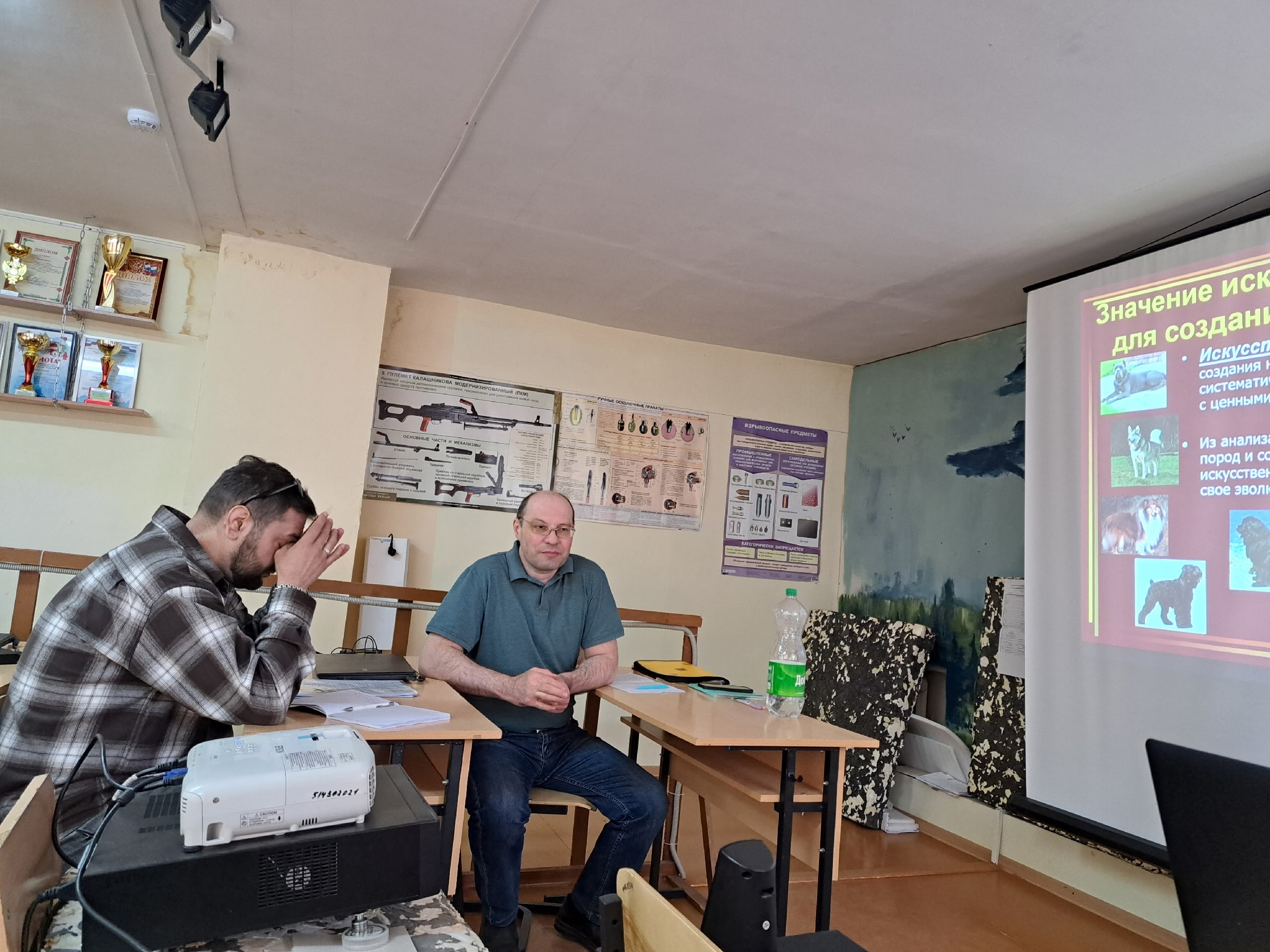 Мужчина сидит за партой в учебном классе перед проектором