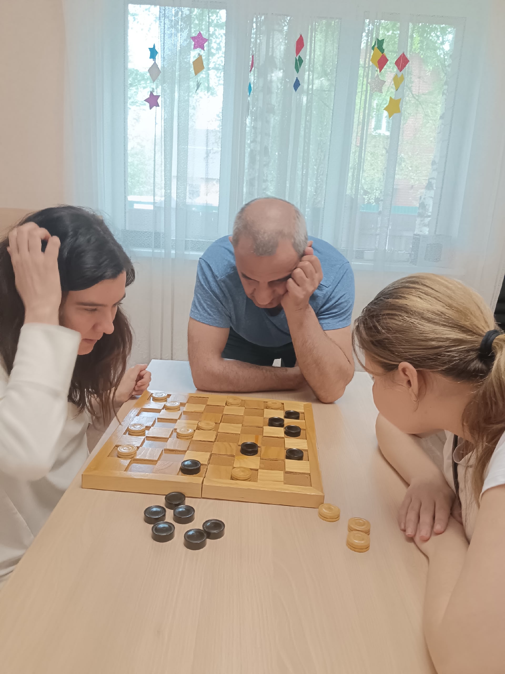 Женщины и мужчина играют в шашки