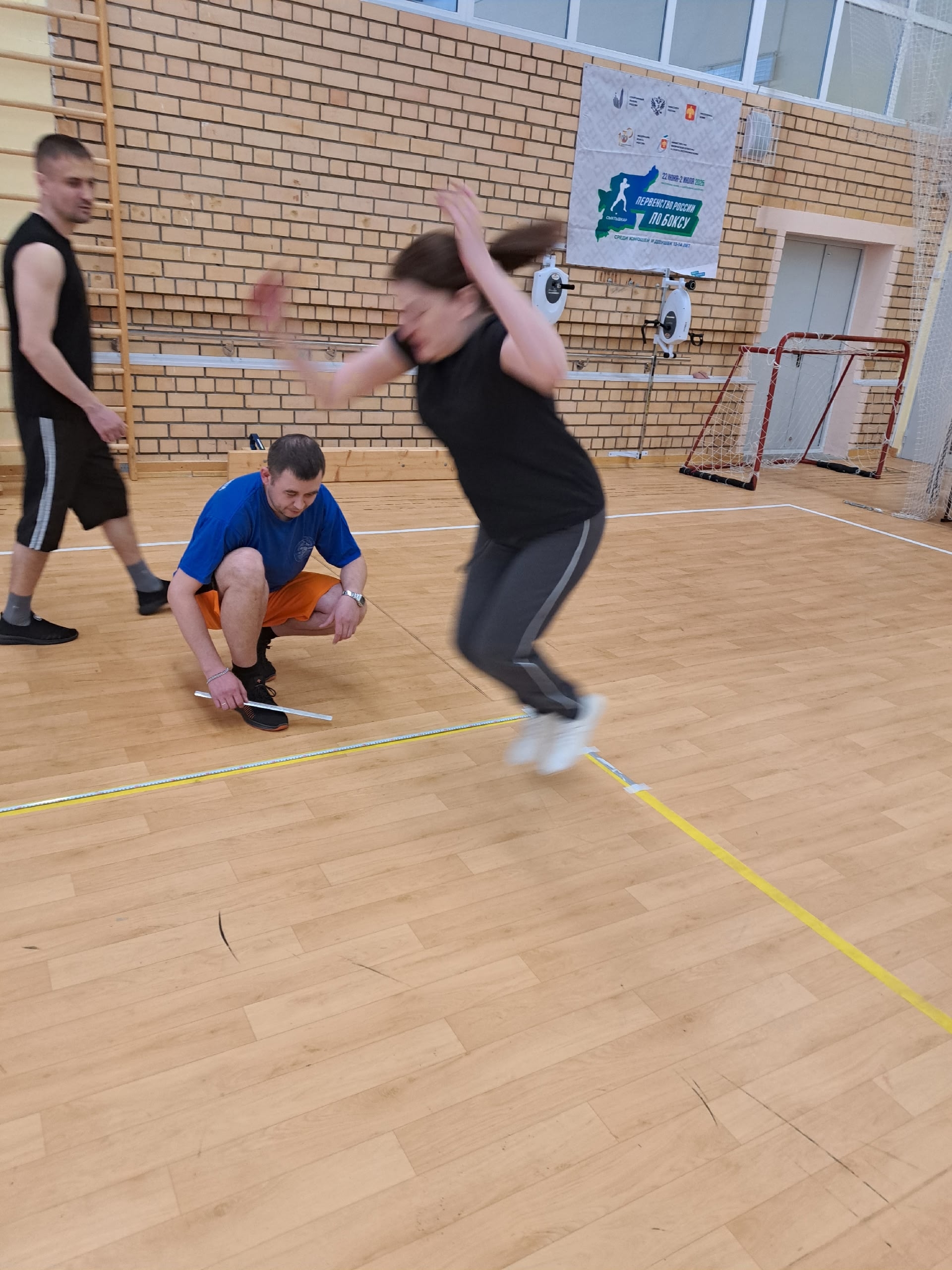Женщина в прыжке, мужчина измеряет результат