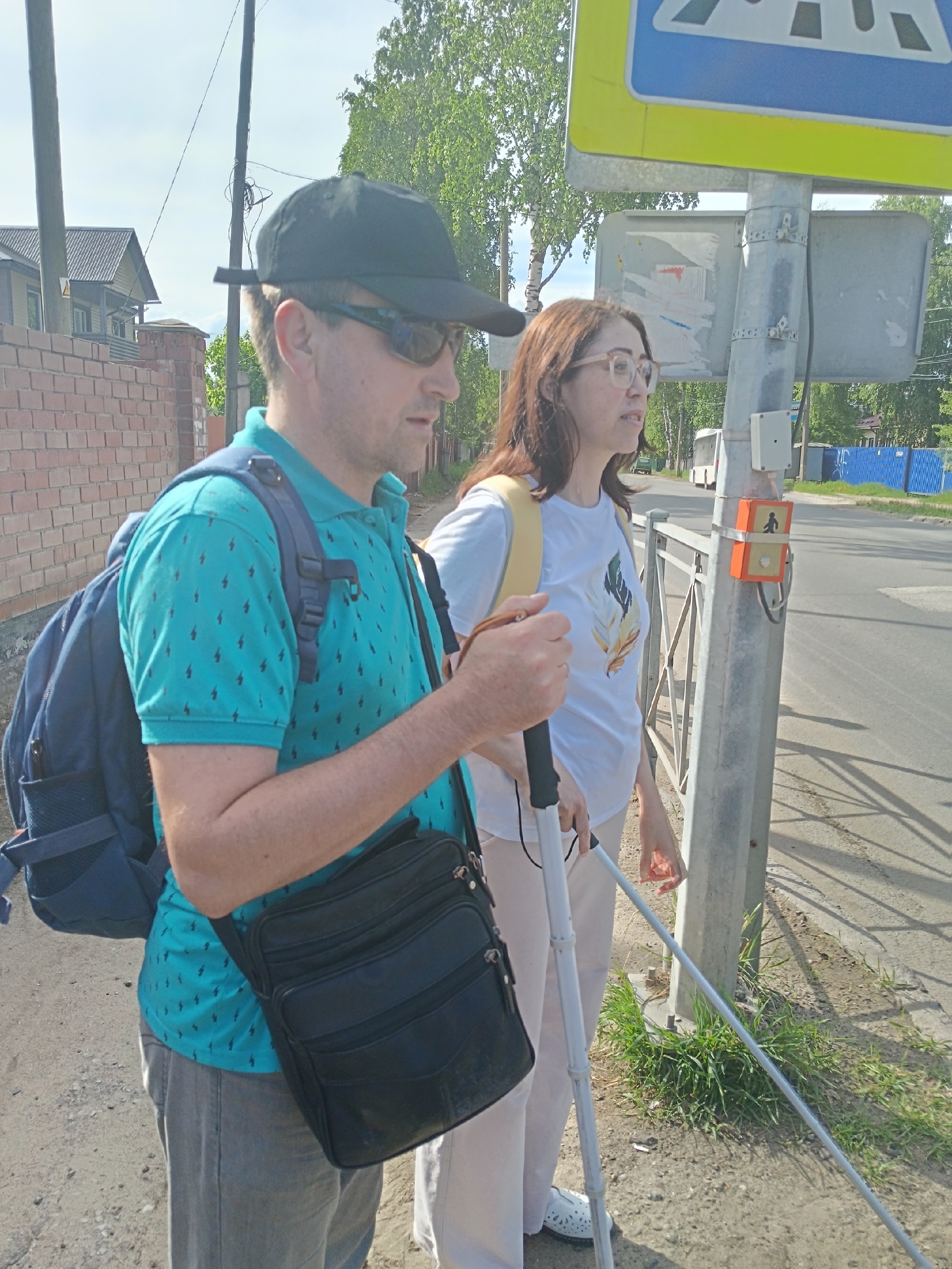 Мужчина и женщина стоят у дорожного знака пешеходного перехода