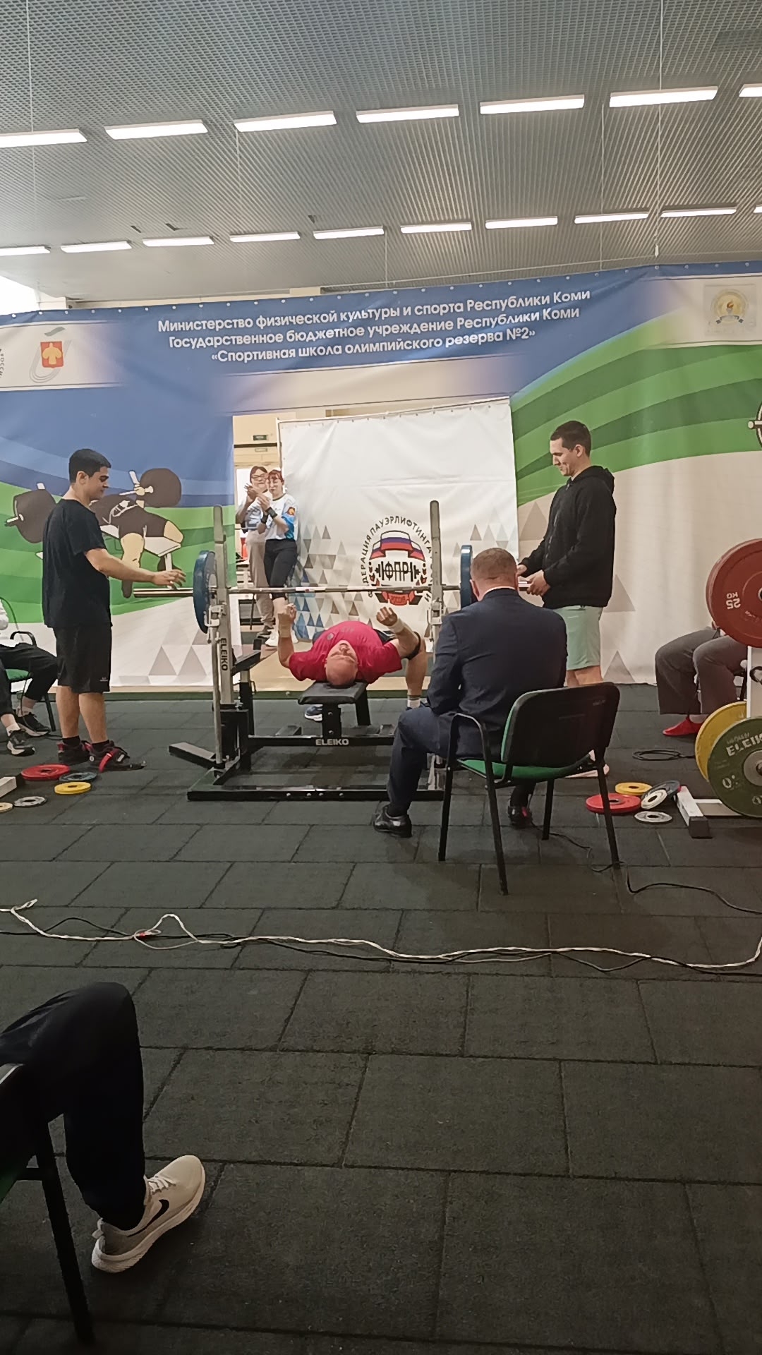 Спортсмен в красной футболке выполняет жим штанги лежа