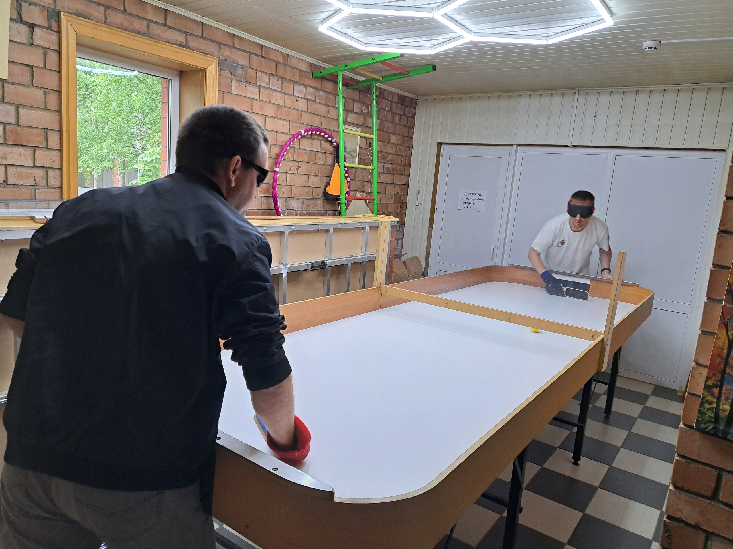 Двое мужчин в защитных очках играют в настольный теннис на специальном столе