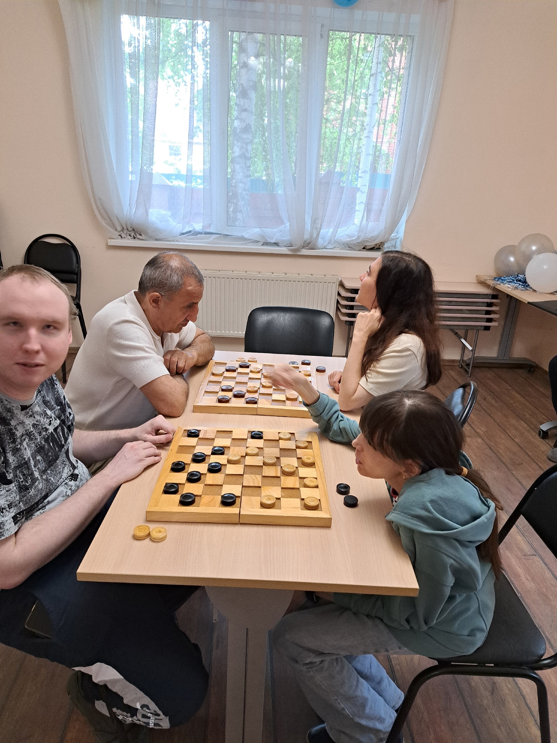 Группа людей играет в настольную игру в шашки