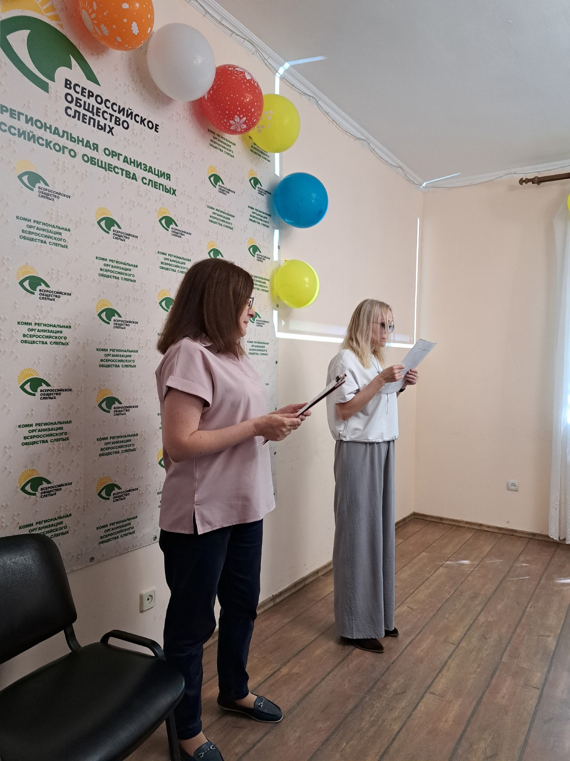 Две женщины выступают с документами на сцене