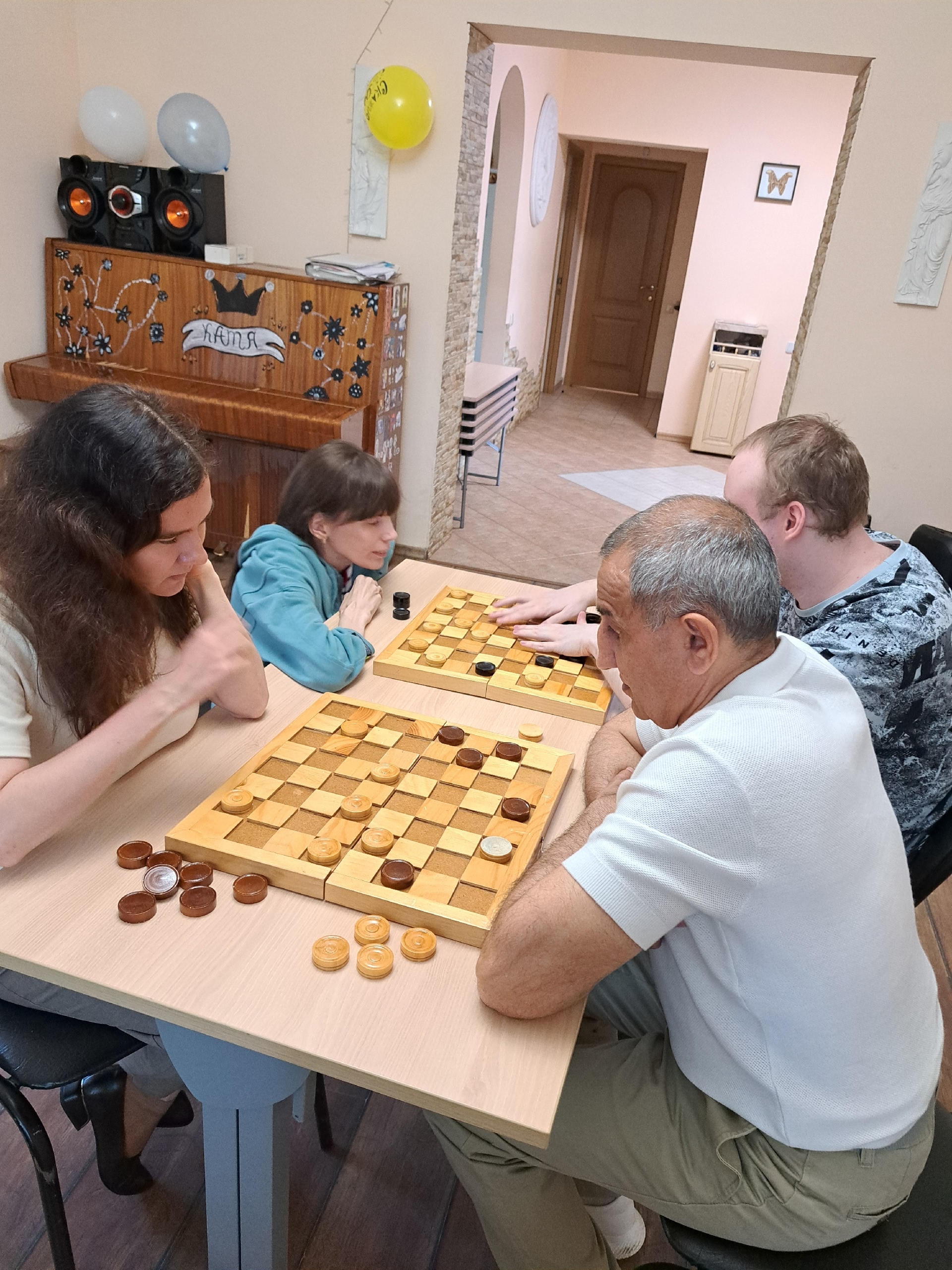 Четверо людей сидят за столами и играют в шашки