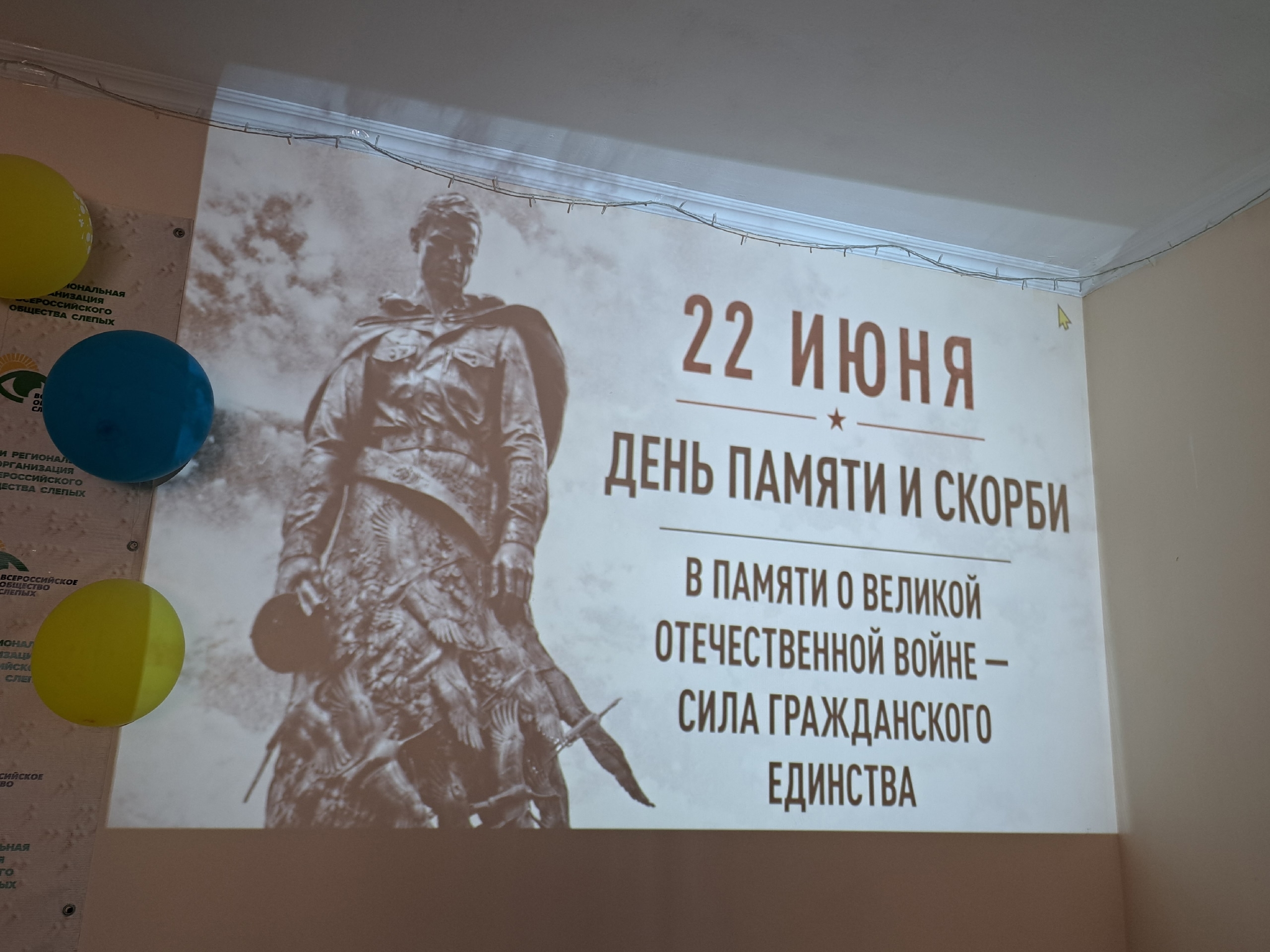 Проекция памятника солдату и надписи о Дне памяти на стене
