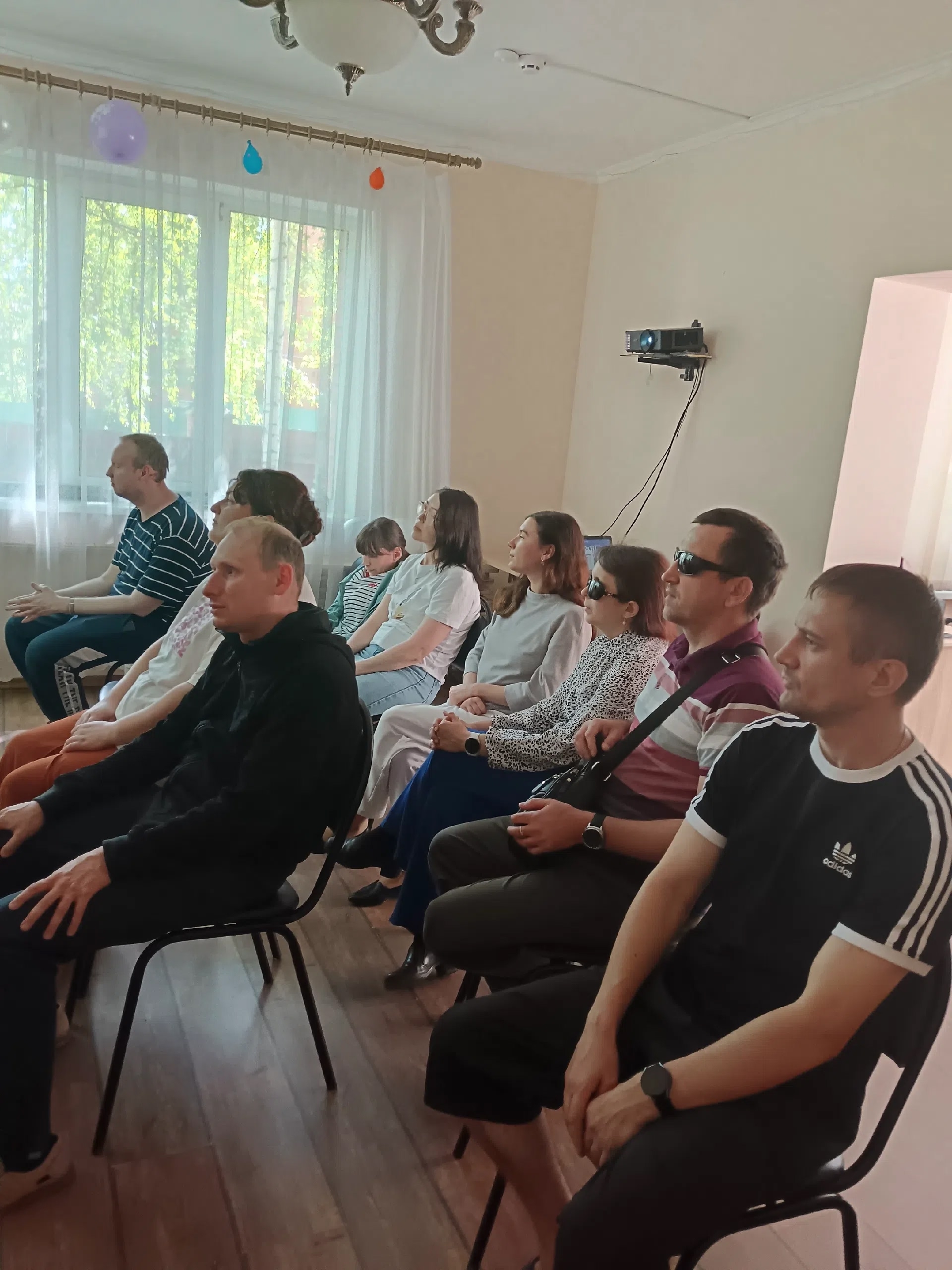 Зрители сидят на стульях в помещении и внимательно смотрят презентацию