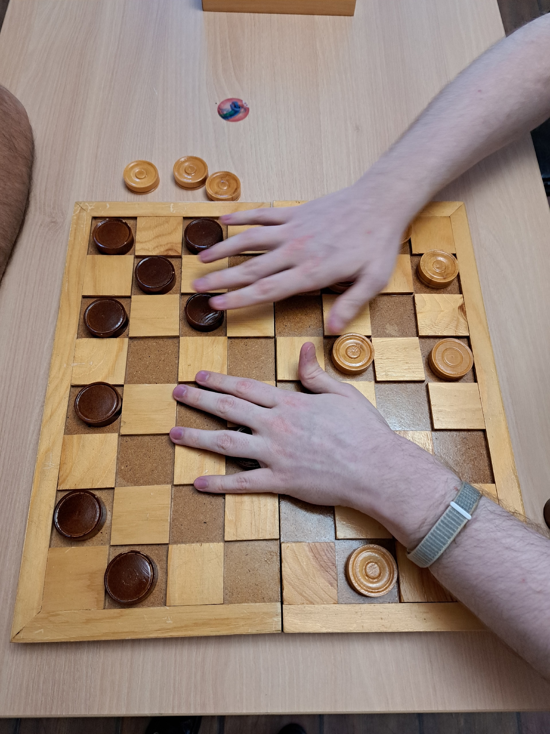 Руки игрока перемещают шашки по игровому полю