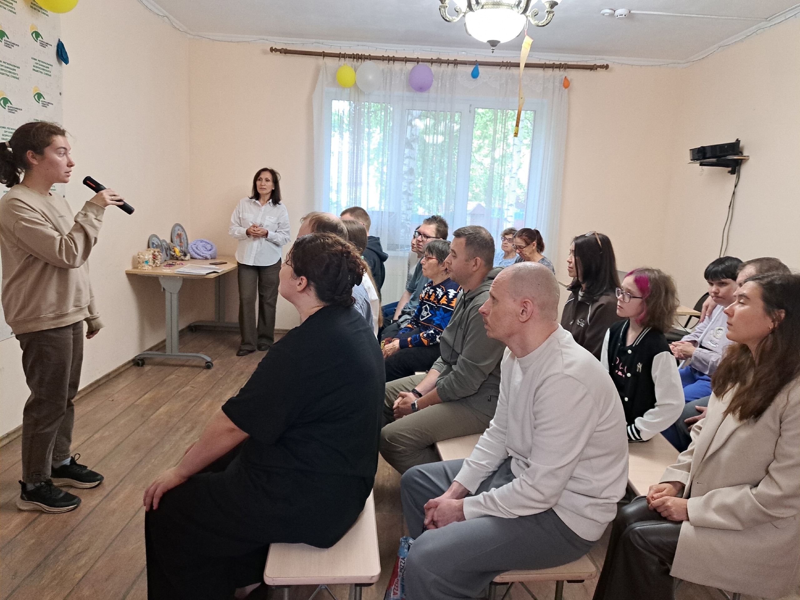 Девушка с микрофоном выступает перед сидящими зрителями