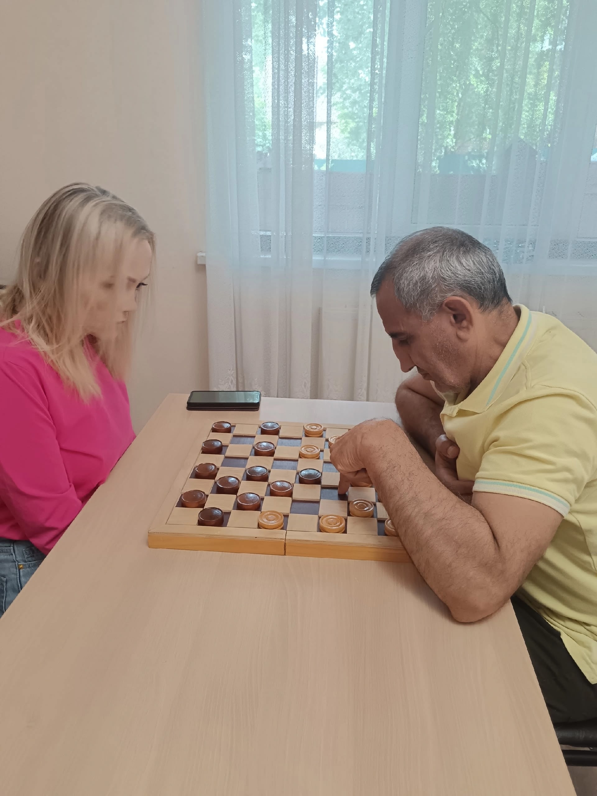 Игроки сосредоточенно смотрят на доску для шашек