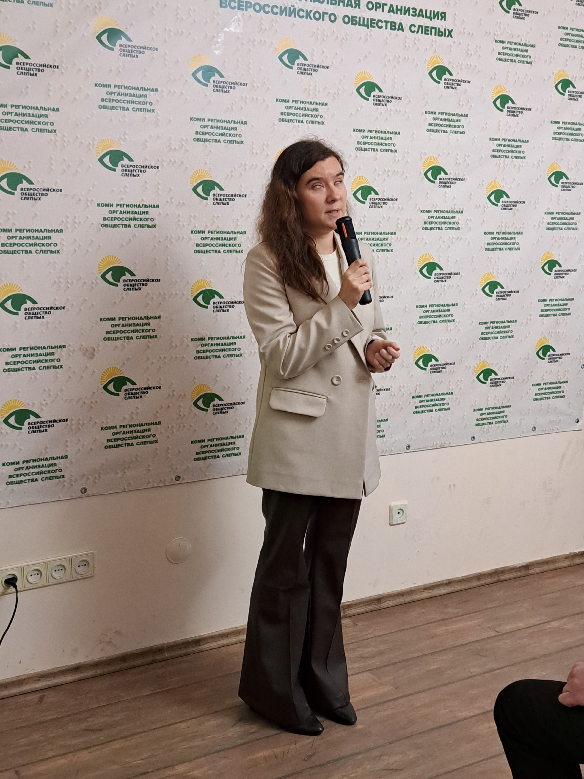 Женщина в светлом пиджаке говорит в микрофон