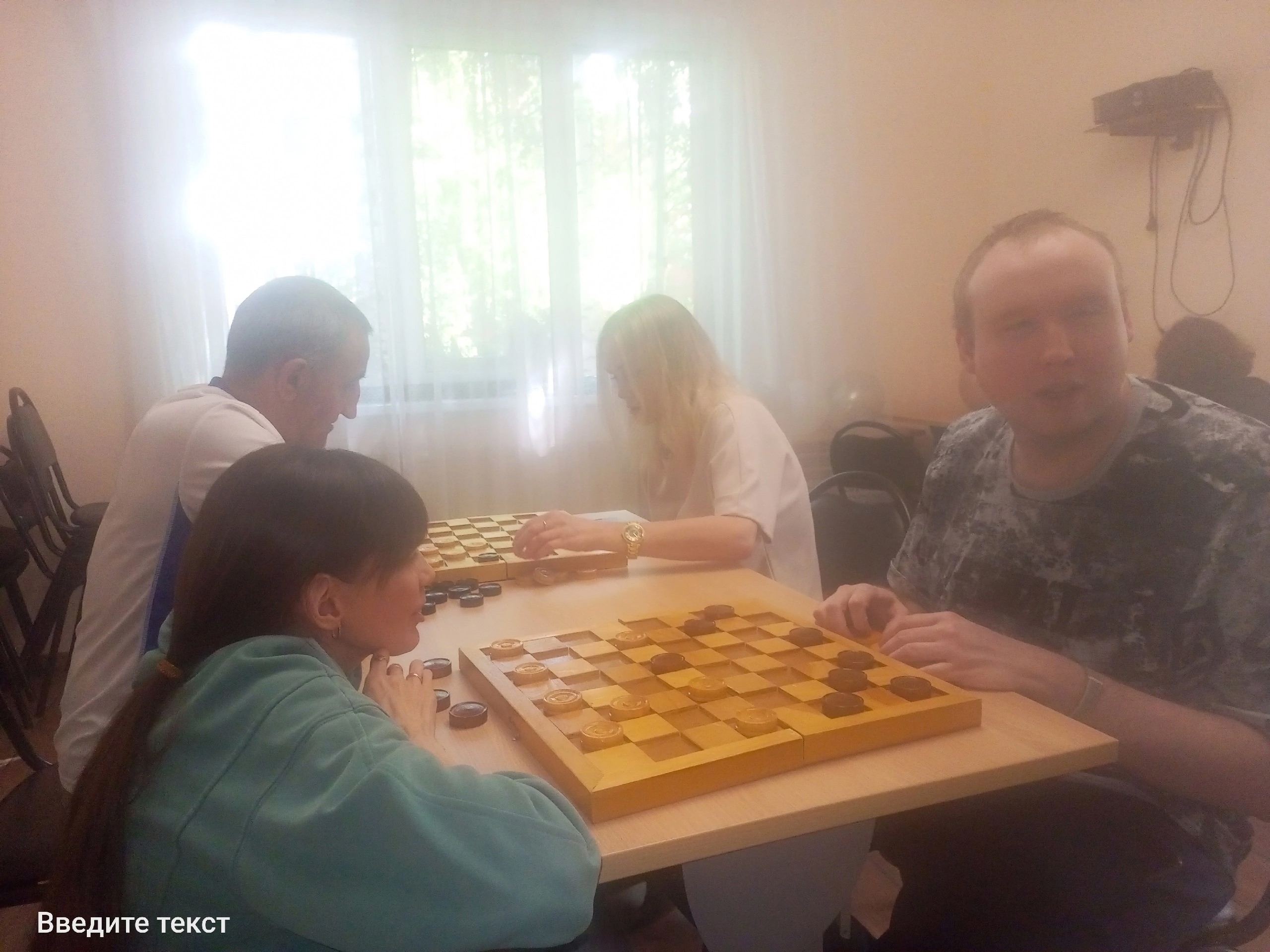 Группа людей играет в шашки в светлом помещении