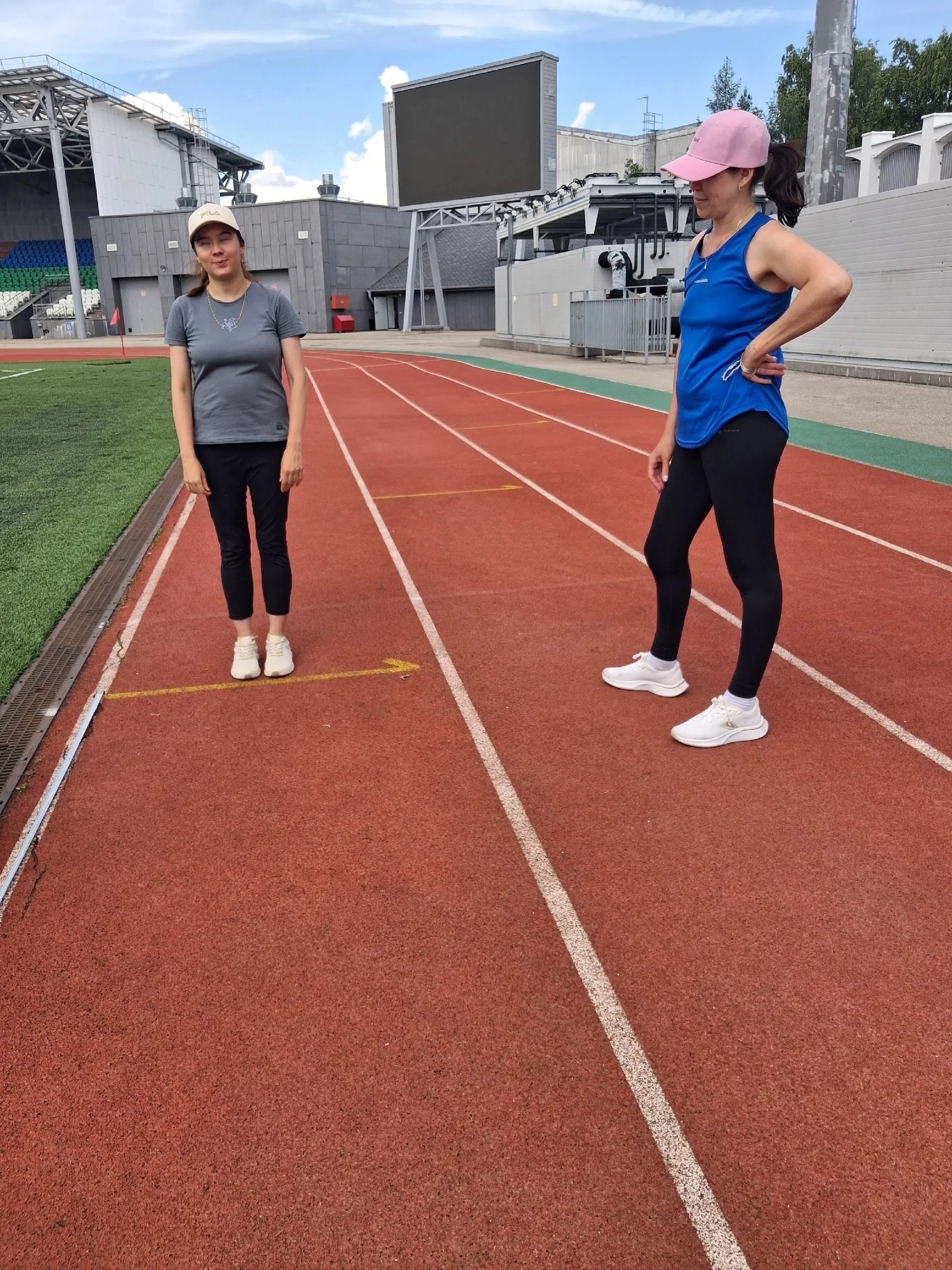Две женщины в спортивной форме стоят на красной беговой дорожке