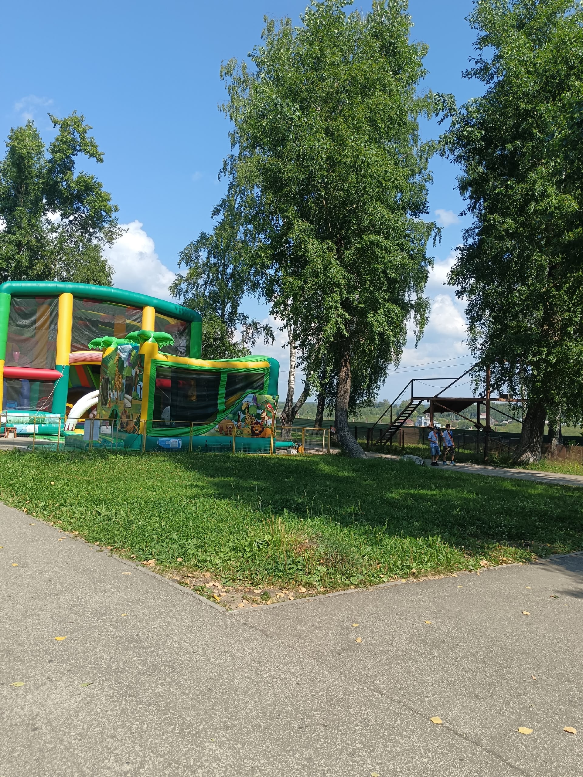 Надувной детский батут зеленого цвета на зеленом газоне в парке