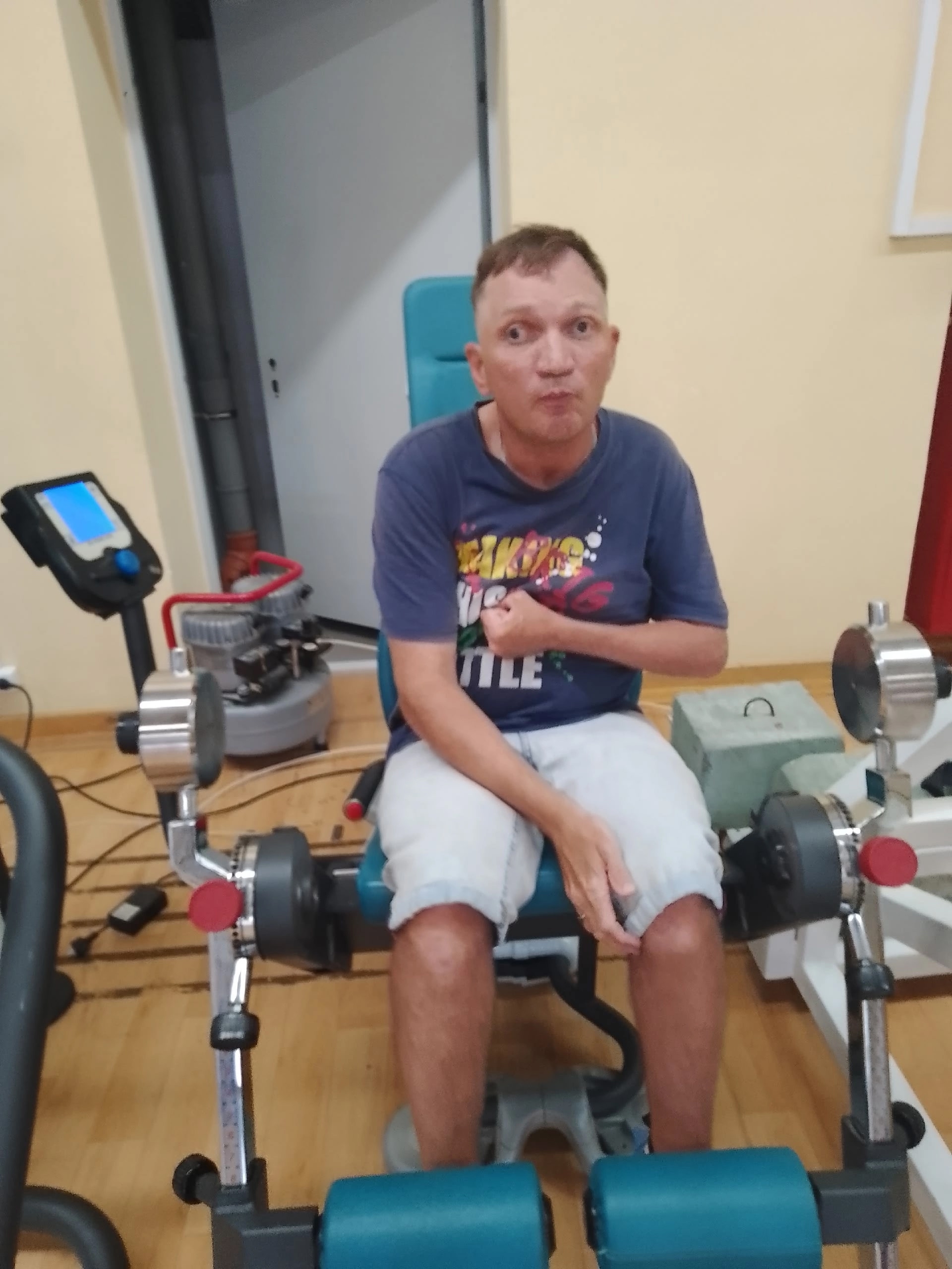 Мужчина сидит на тренажере для ног в спортивном зале