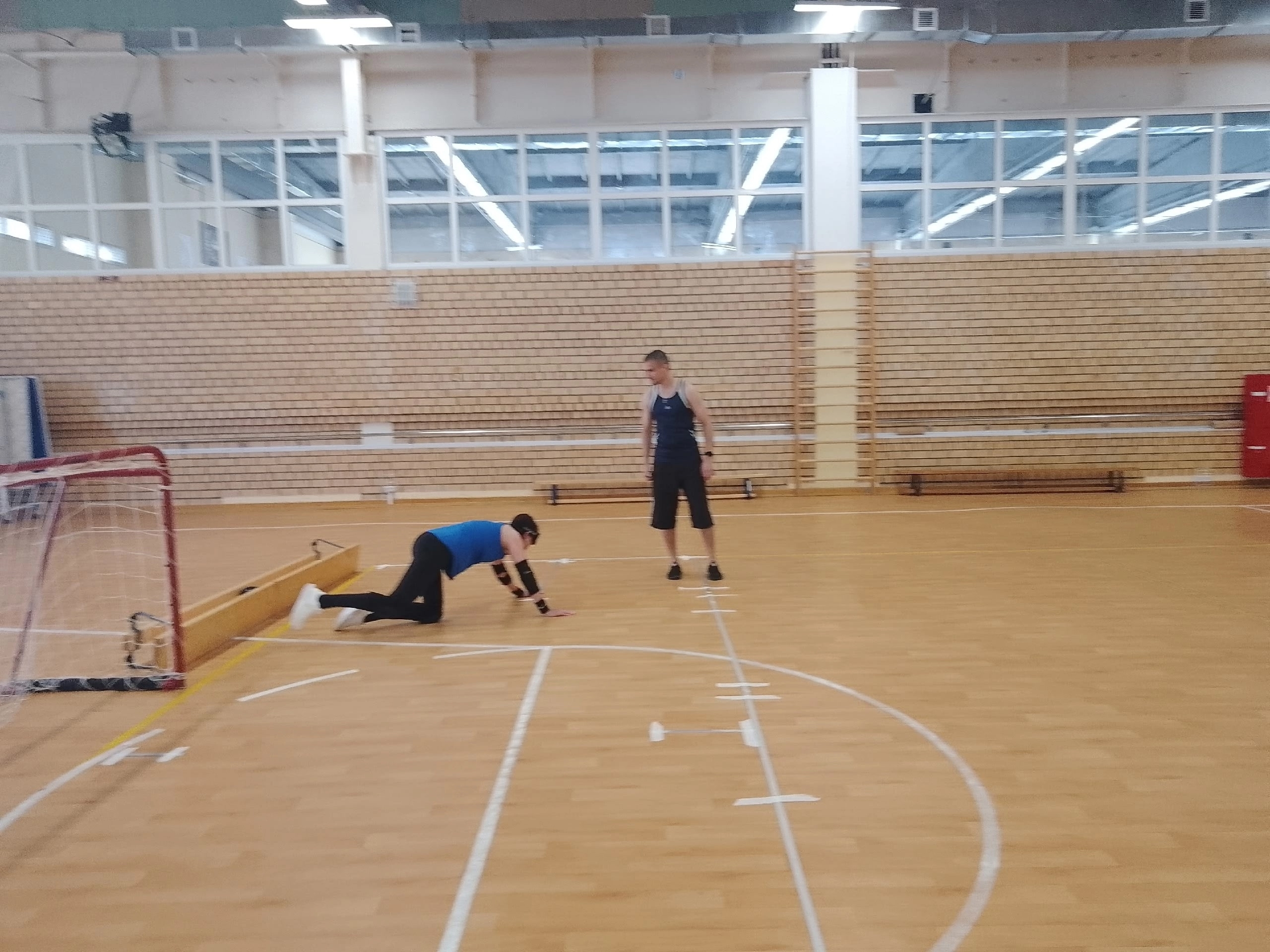 Спортсмен в защитных очках ползет по полу спортивного зала