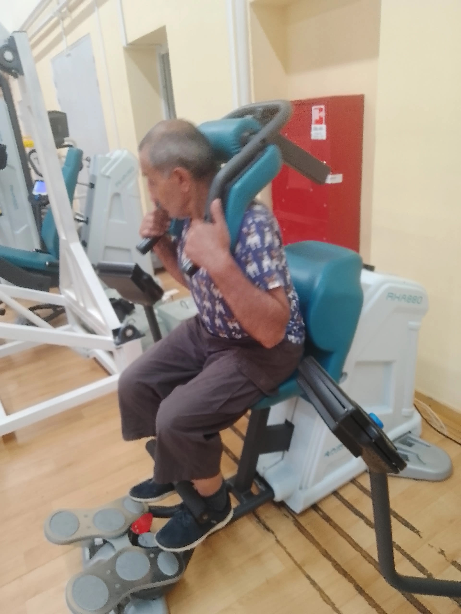 Мужчина сидит на специальном тренажере во время тренировки