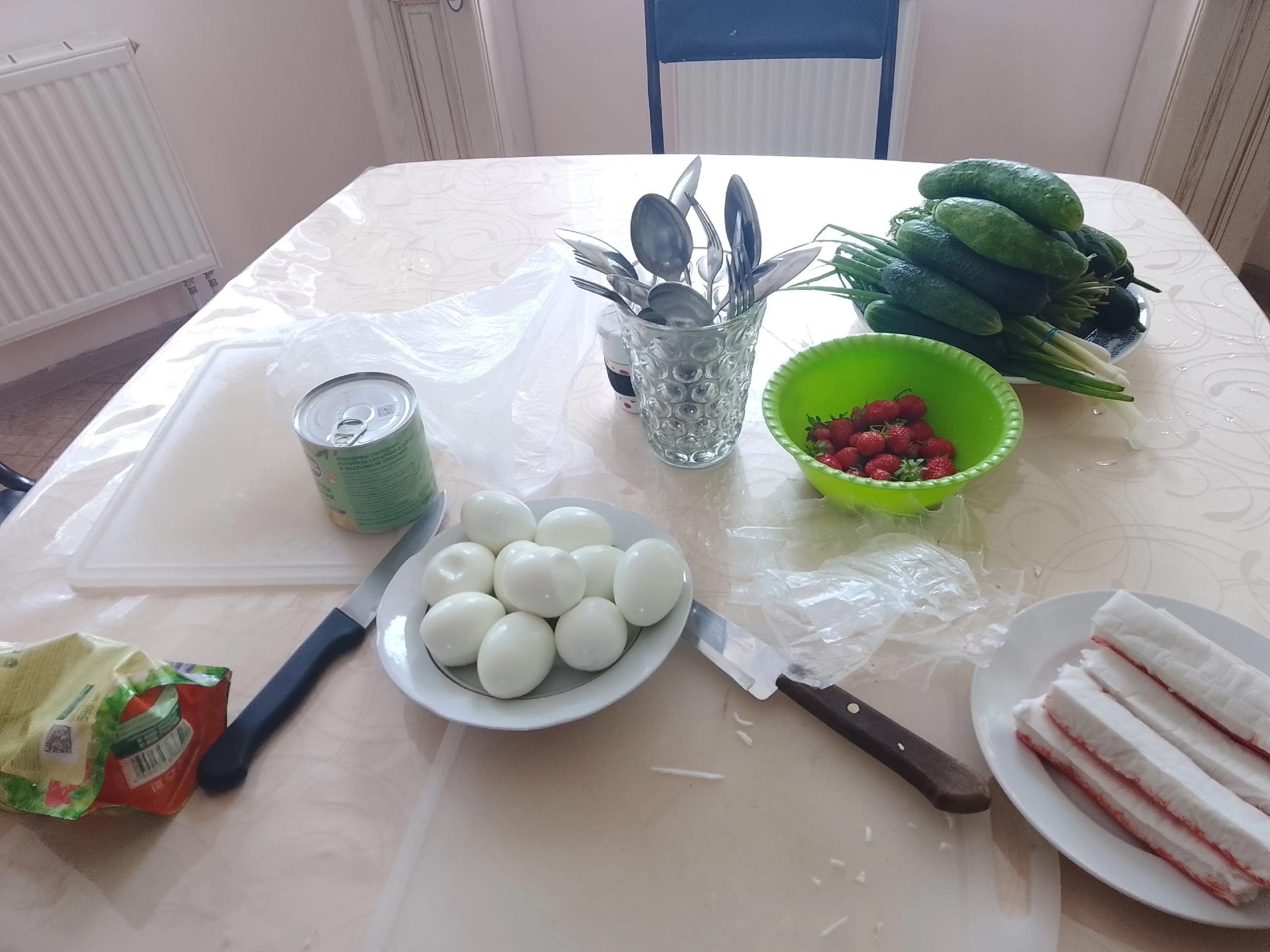 Ингредиенты для обеда на столе: вареные яйца, крабовые палочки, огурцы и клубника