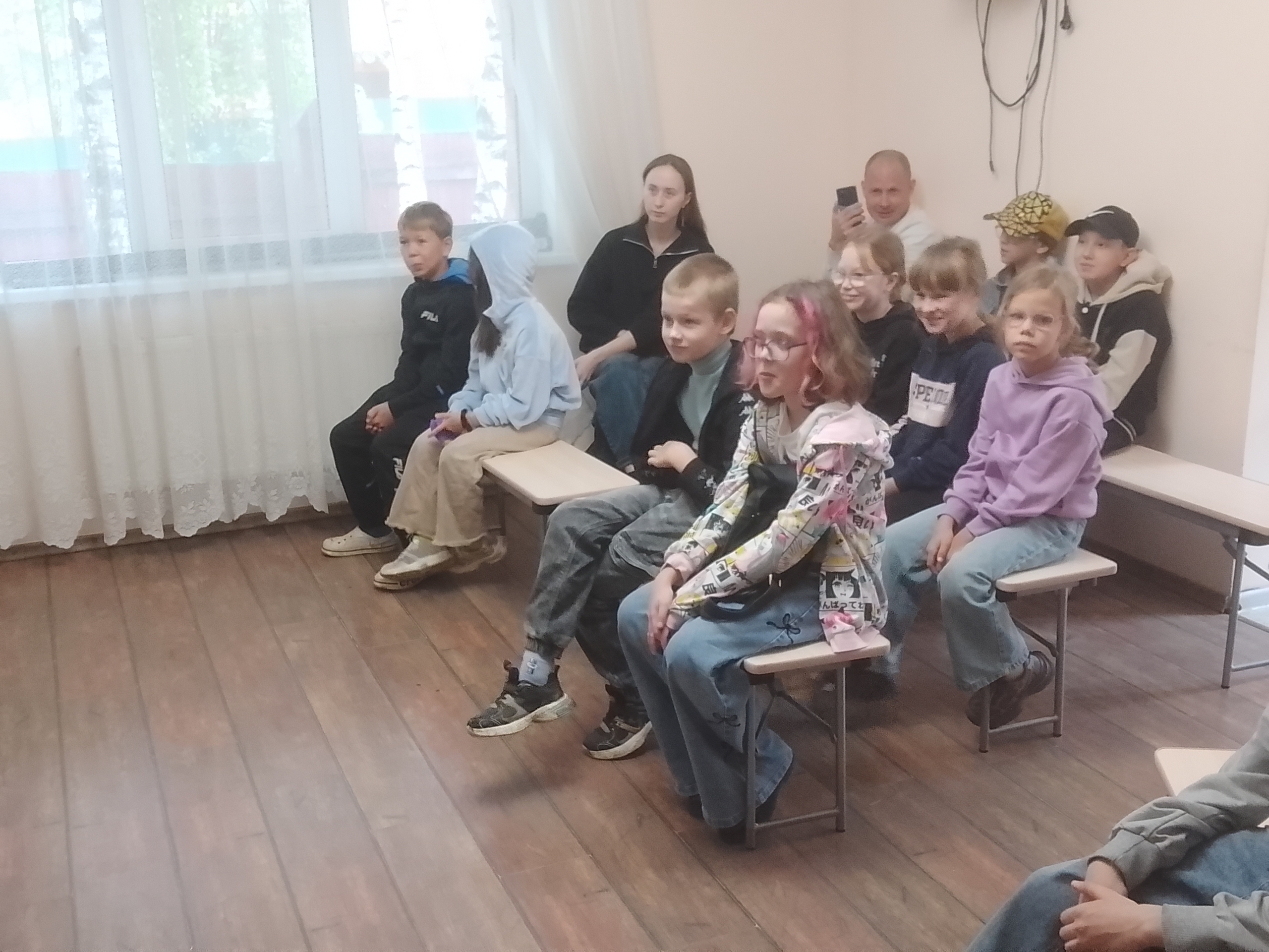 Дети сидят на скамейках в комнате и смотрят представление