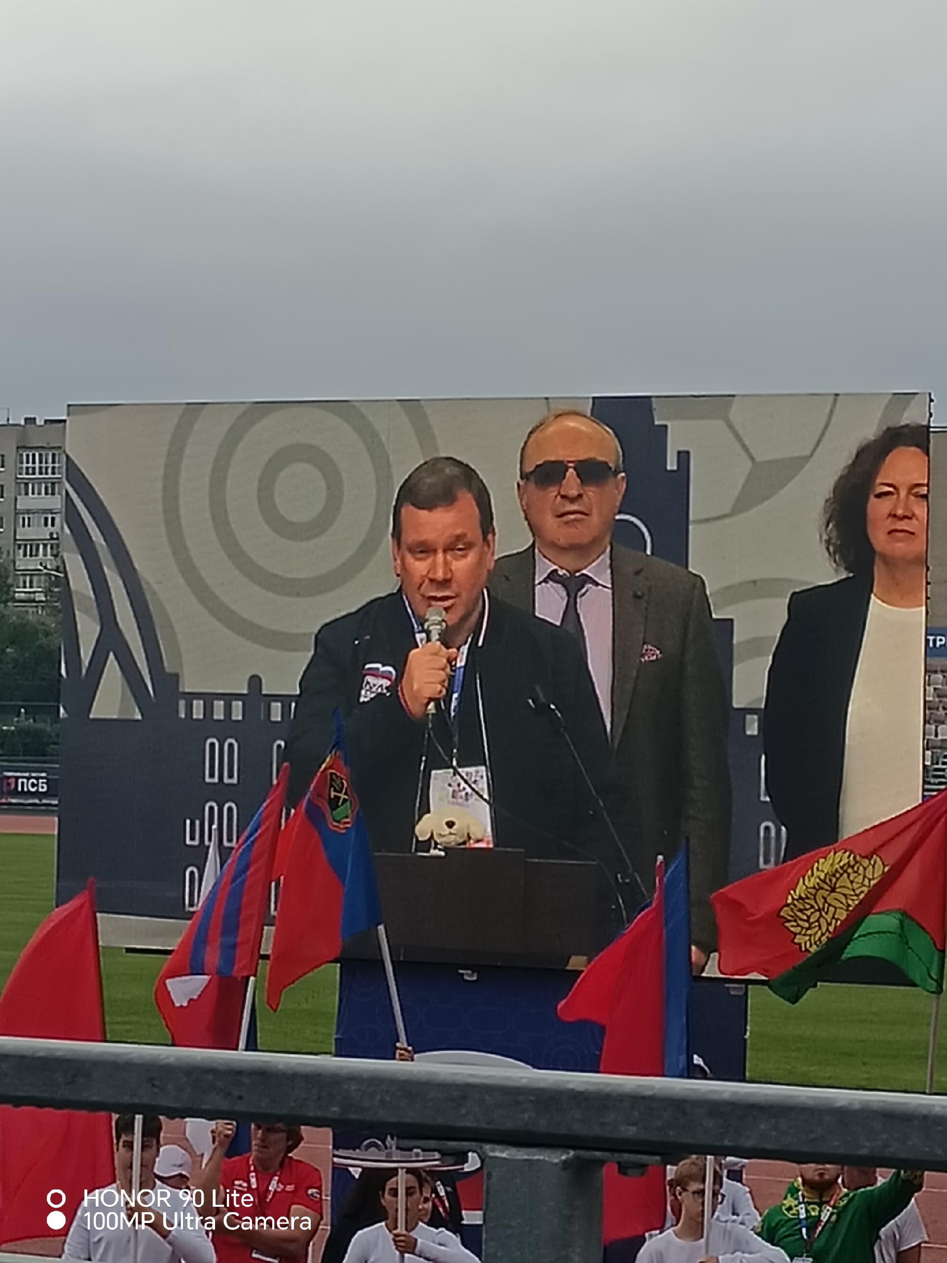 Выступление спикера у трибуны с микрофоном на фоне большого экрана