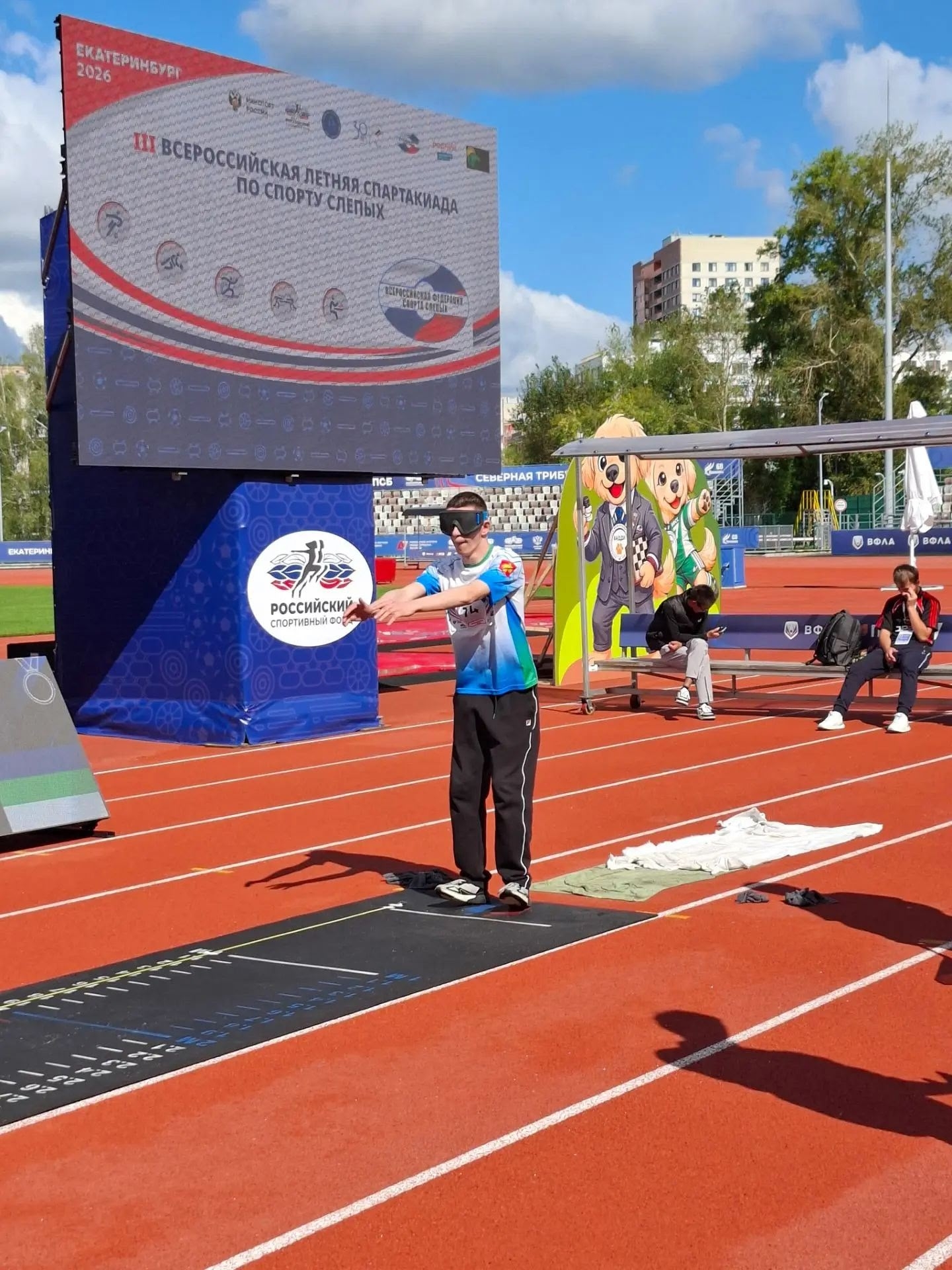 Спортсмен в светонепроницаемых очках готовится к прыжку в длину с места