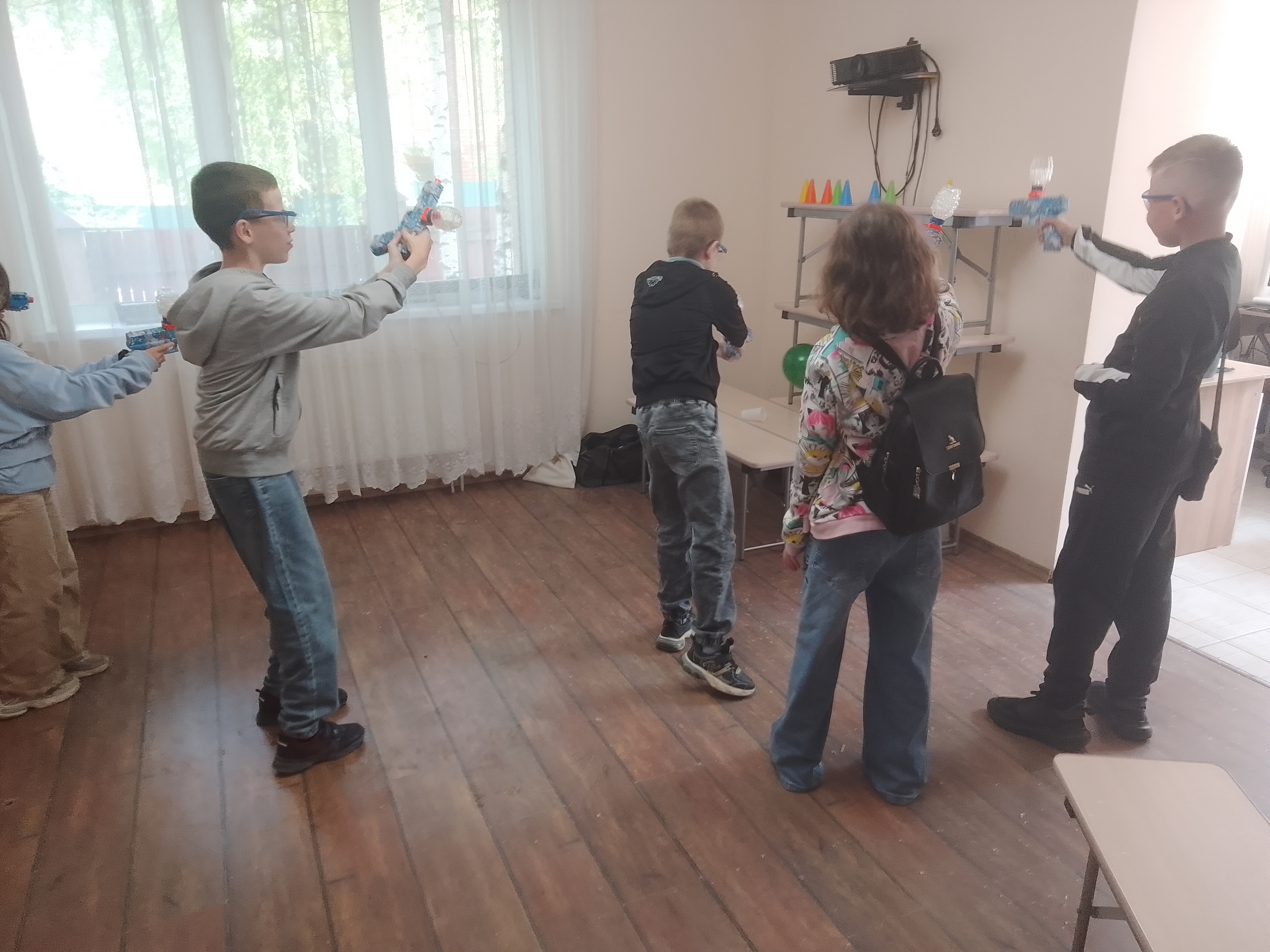Дети с игрушечным оружием прицеливаются в мишени из стаканчиков