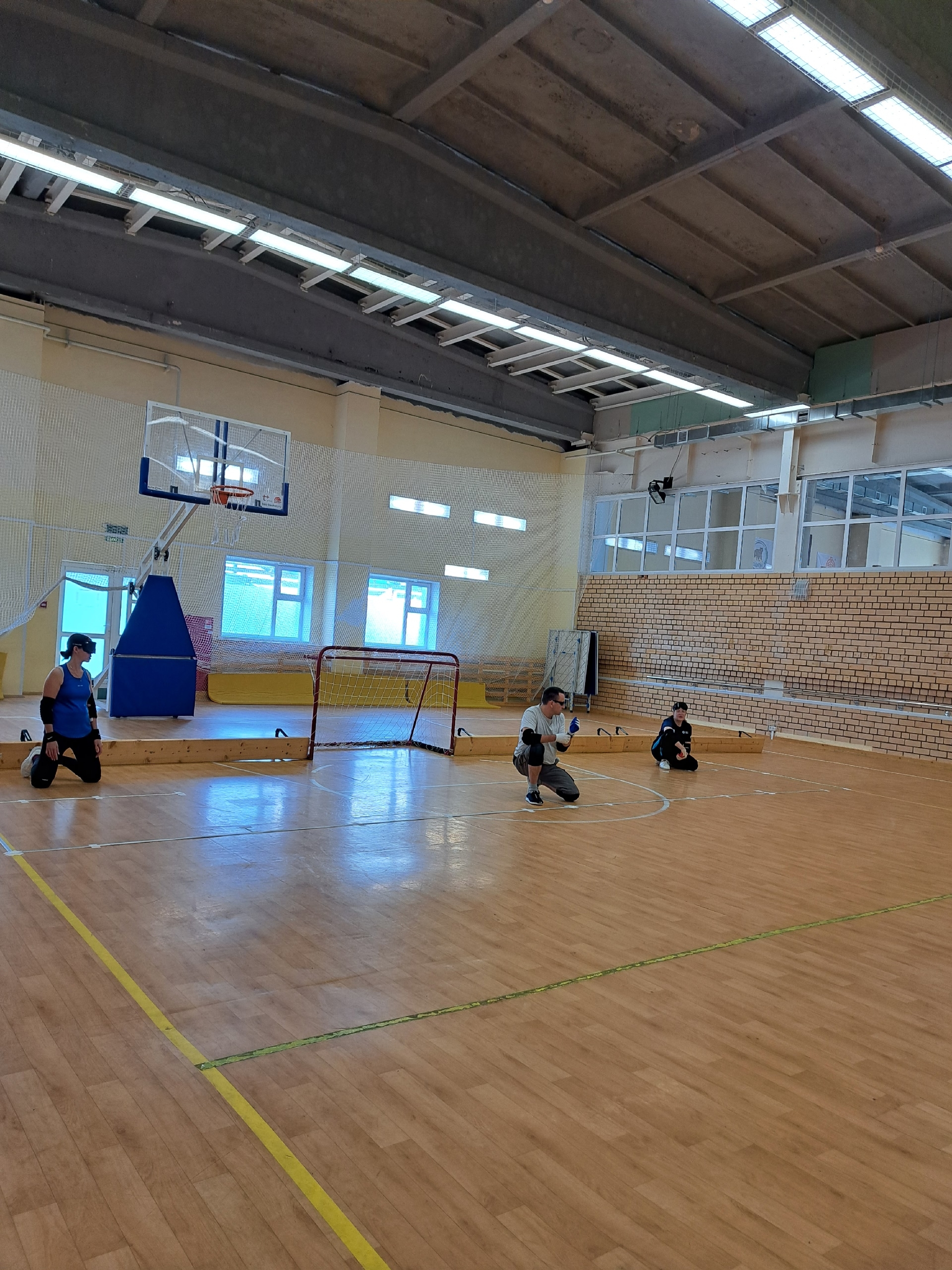 Спортсмены в масках для голбола тренируются на площадке в спортивном зале