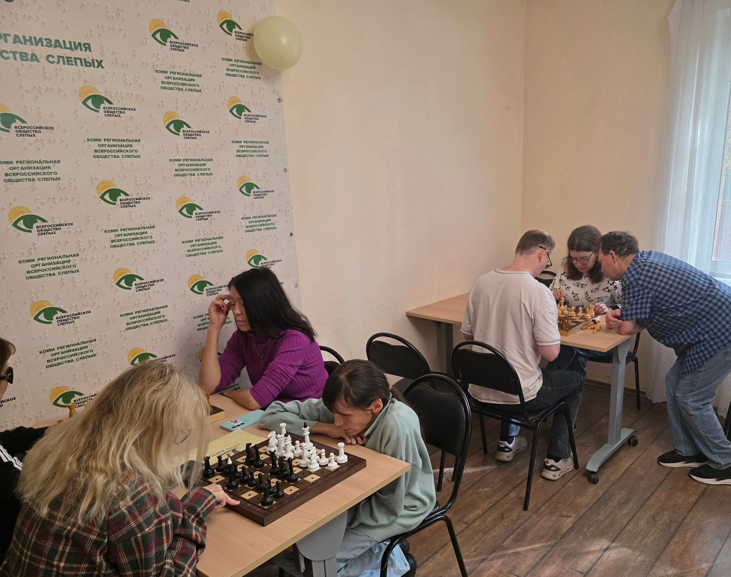Несколько пар участников изучают шахматные фигуры и доски за столами